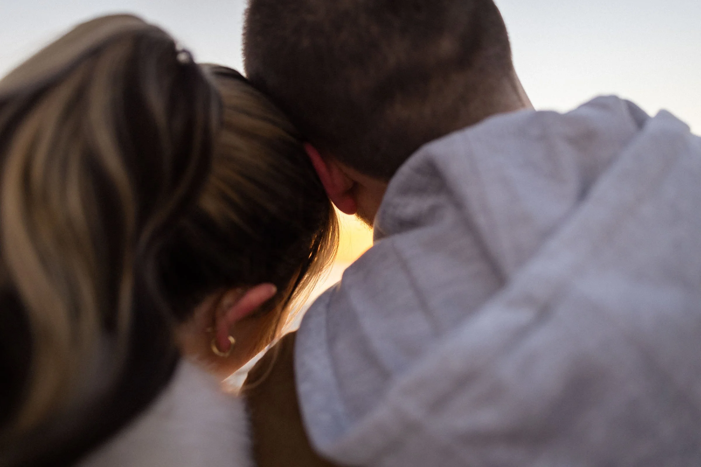  couple with heads together with sunset between them 