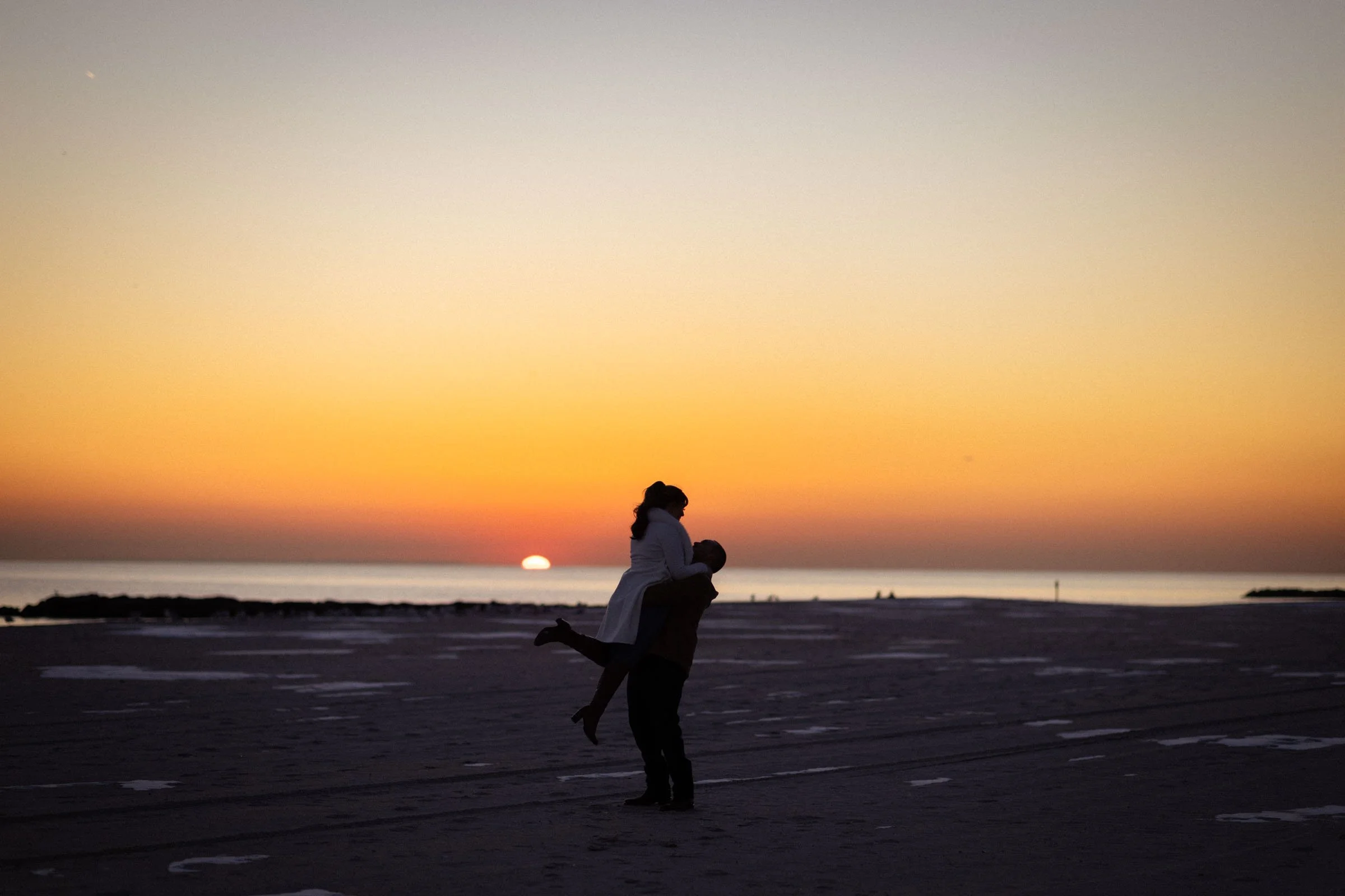  Man picking up woman during sunset on beach 