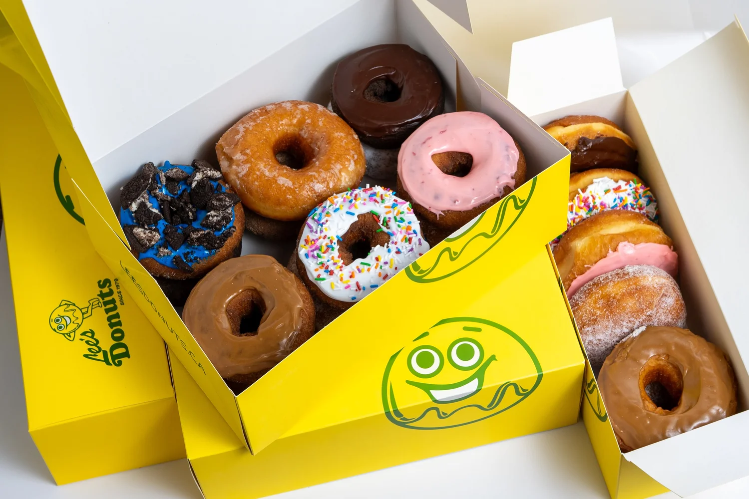 Yellow Lee's Donuts boxes filled with glazed, chocolate, sprinkle and jam-filled donuts