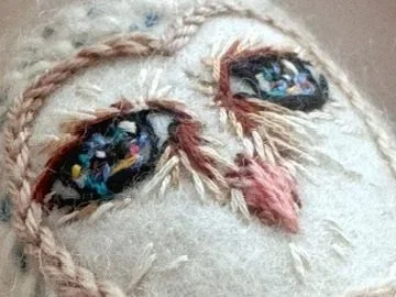 Escultura de cerámica blanca con imagen de totem bordado