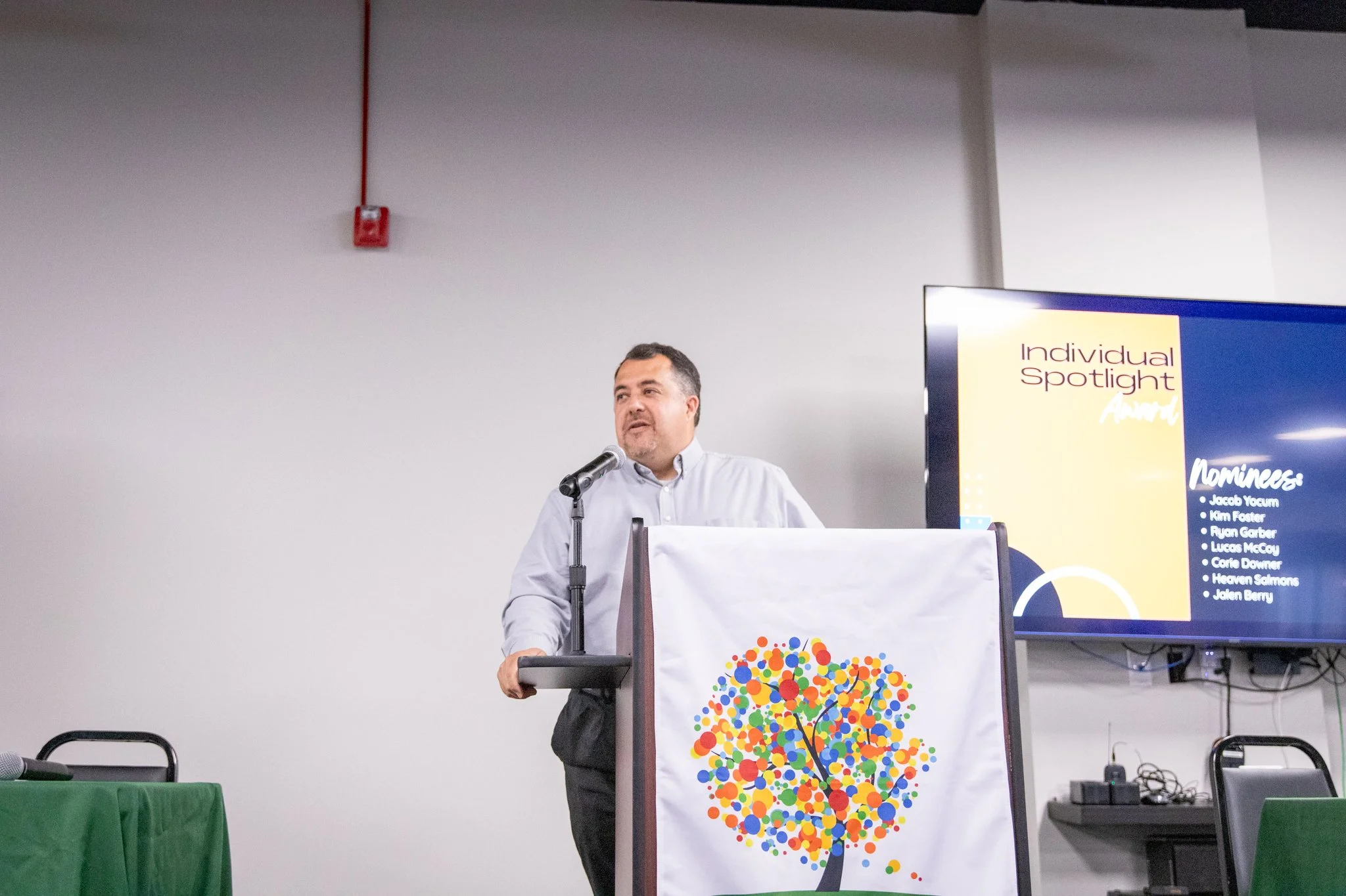 image of man standing on a stage, speaking behind a podium.