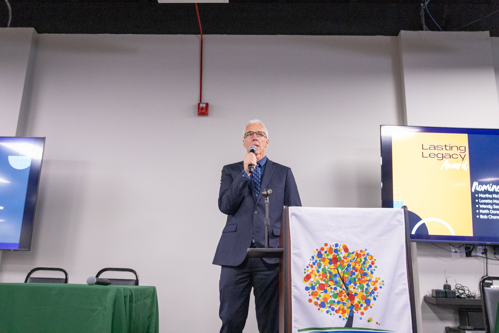 image of man on a stage, speaking into a microphone
