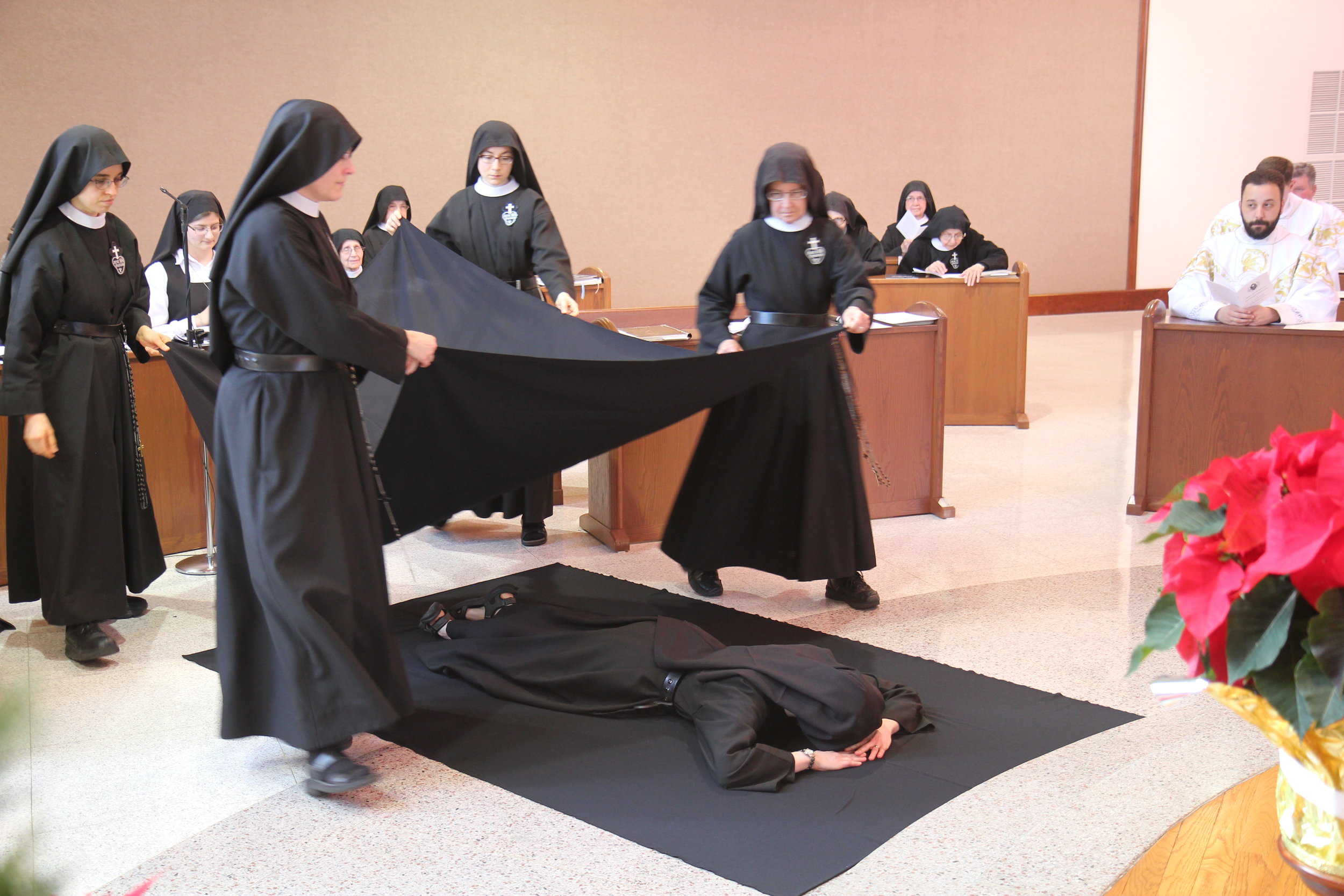  While she lies before the altar, the nuns and guests join in singing the Litany of the Saints, invoking their aid for Sister Cecilia Maria as she prepares for her perpetual consecration to Christ. 