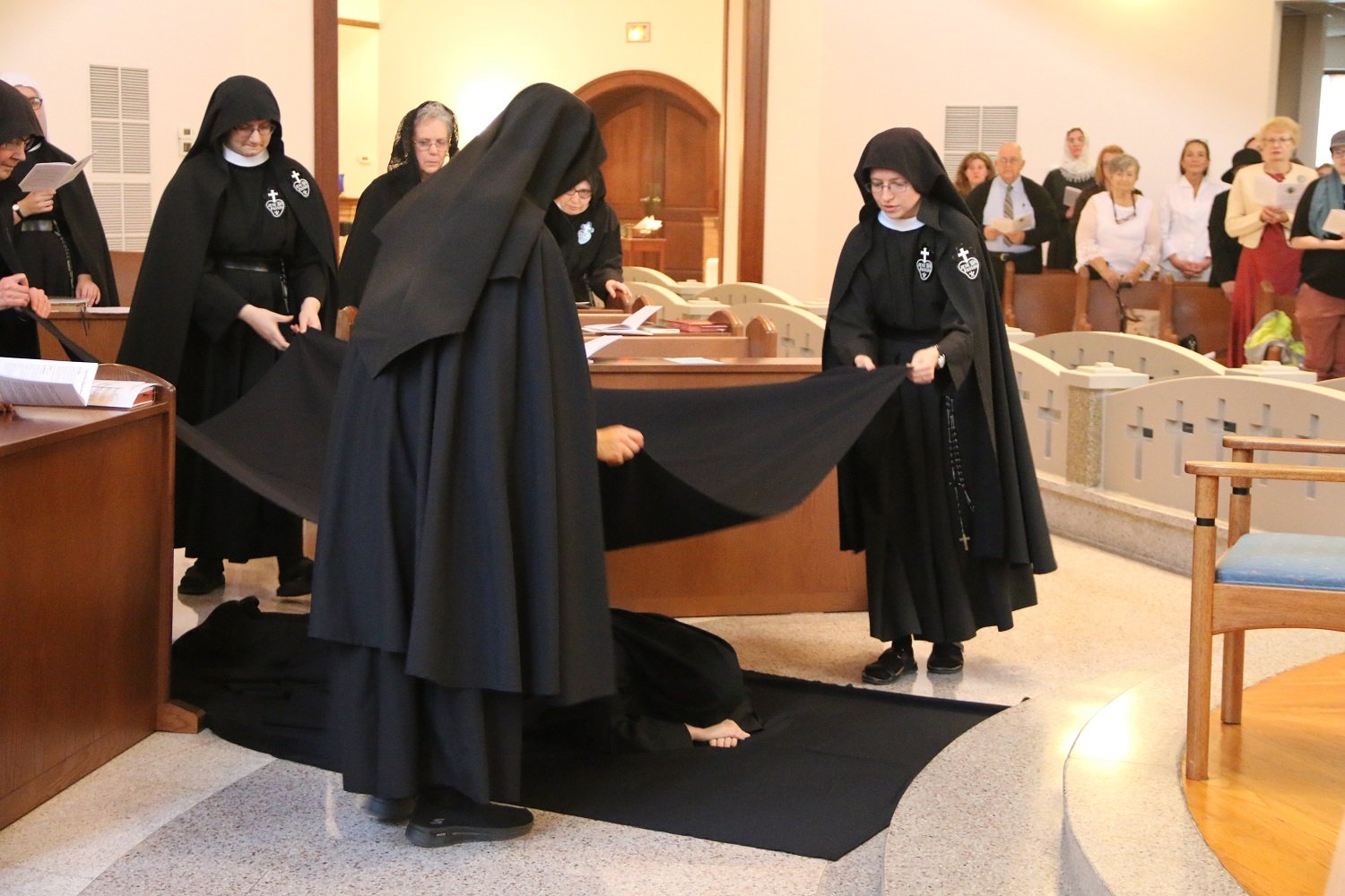  Sr. Maria Faustina falls prostrate before the altar, and her Sisters cover her with a black funeral pall to symbolize her death to self, so that she may rise with Christ.   (Photo: Elizabeth Wong Barnstead, Western KY Catholic)  