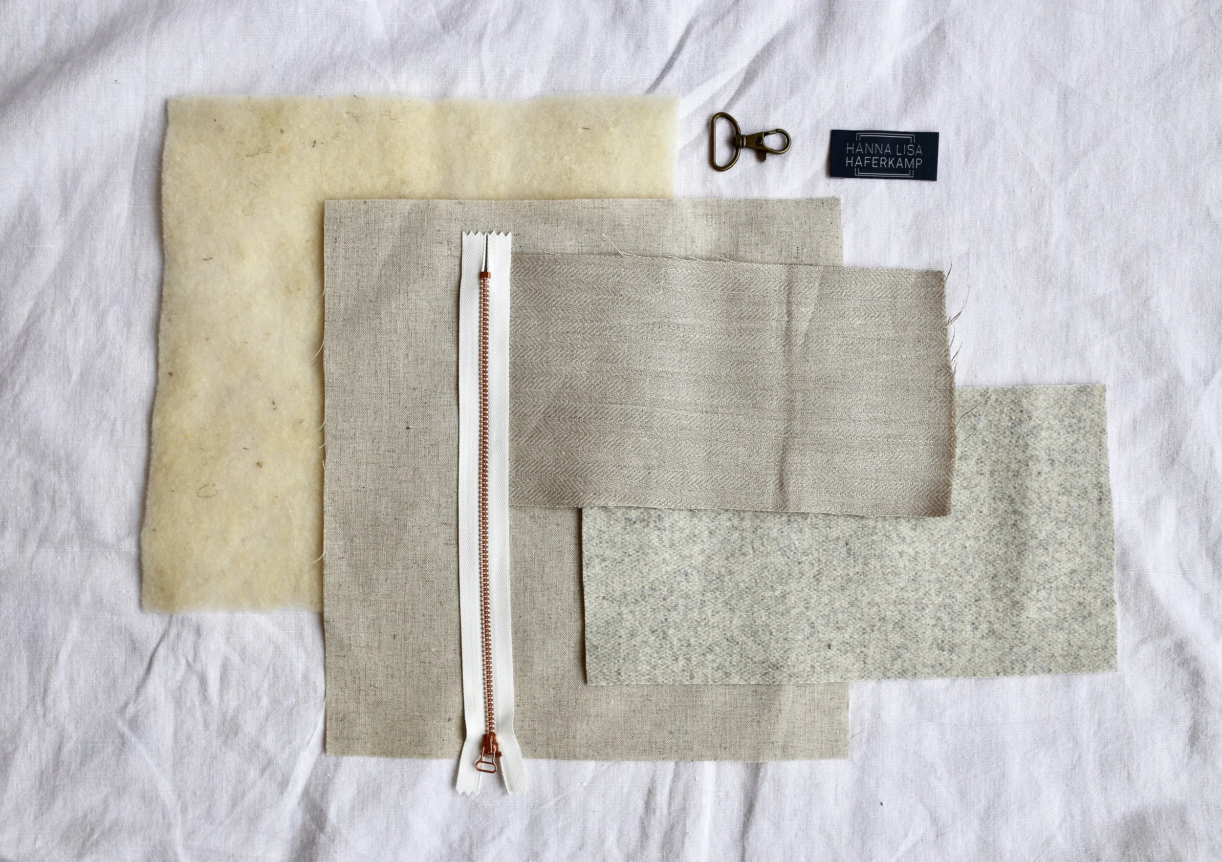 Loosely from left to right: Wool interfacing, linen & viscose lining, zipper, Austrian herringbone linen, wool contrast fabric, carabiner & label.