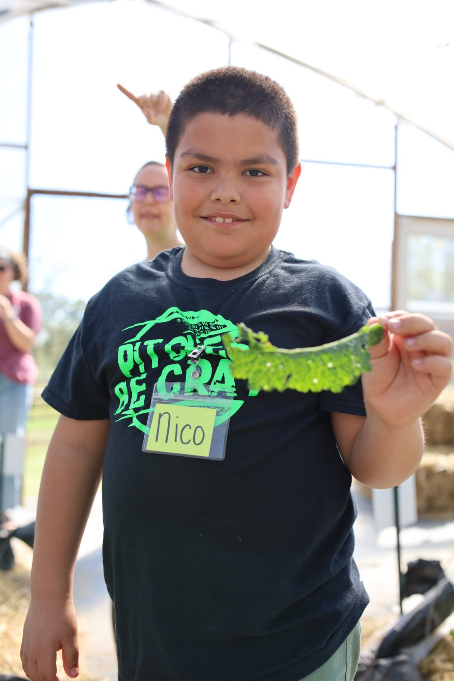 A boy holding a freshly-harvested kale leaf