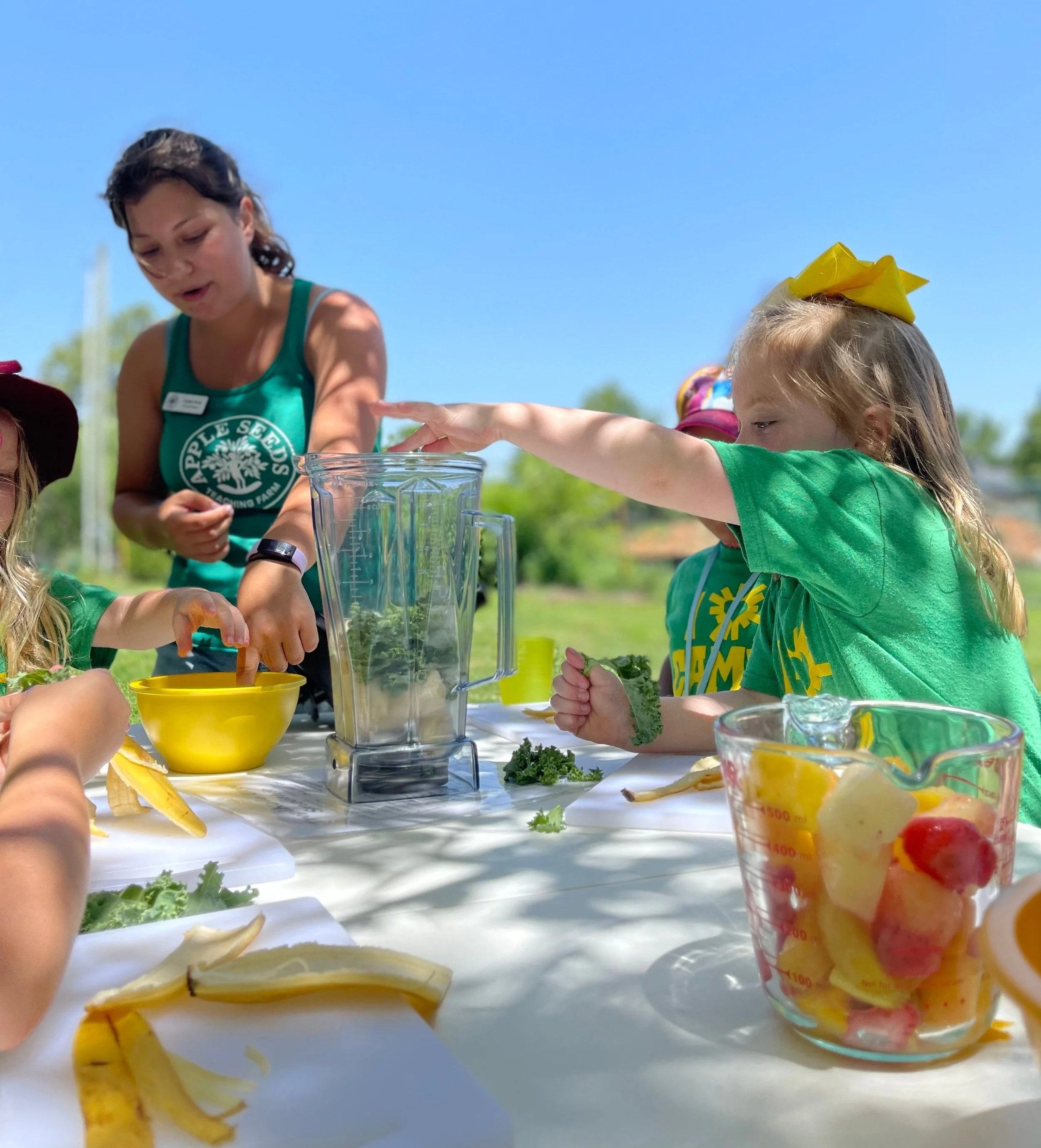 Apple Seeds employee making a groovy greens smoothie with a young girl