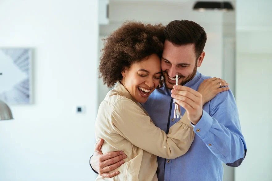 Happy couple hugging and holding keys in a new home.