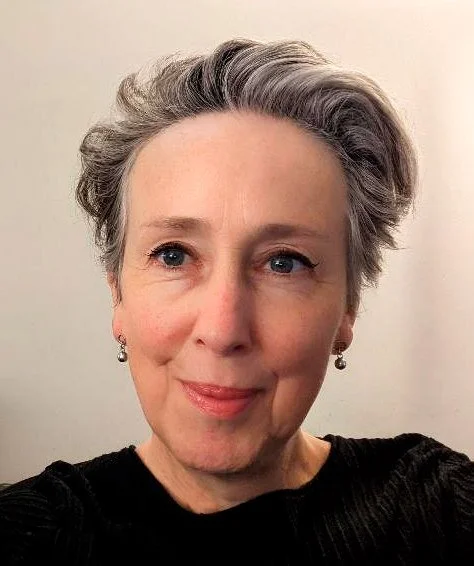 Portrait of Elizabeth Dixon smiling and posing in front of a pale background.