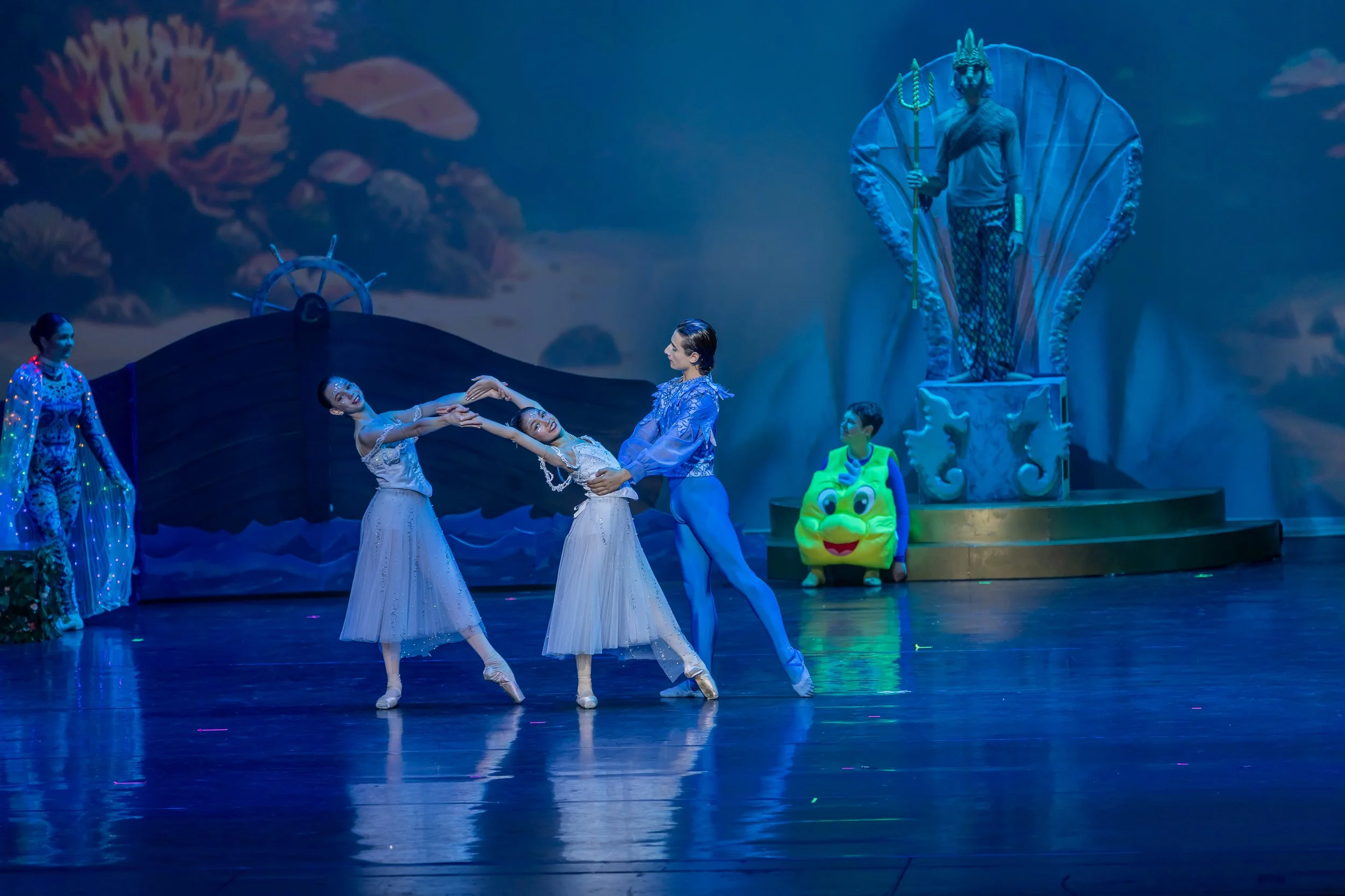 The stage transforms with colorful costumes and dynamic movement during a full-company highlight.