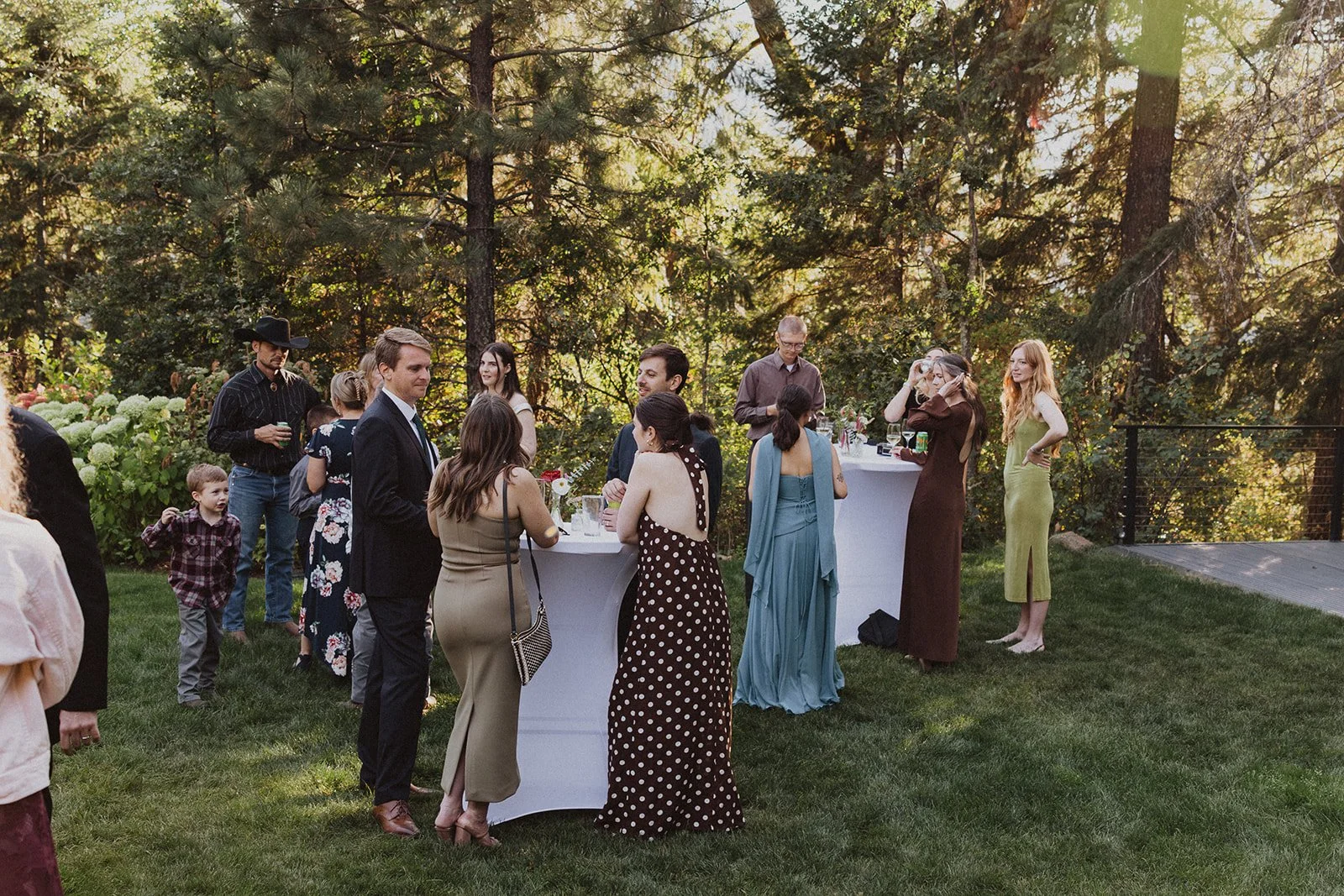 Cocktail hour on the lawn under tall pines at a forest micro wedding