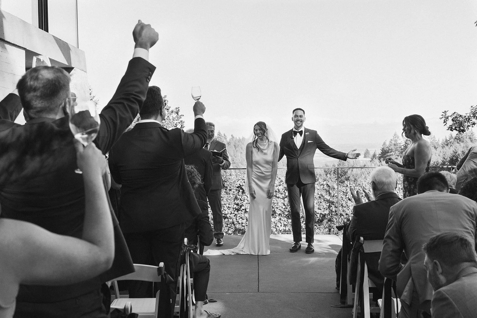 Guests raising wine glasses during an Oregon winery wedding ceremony outdoors