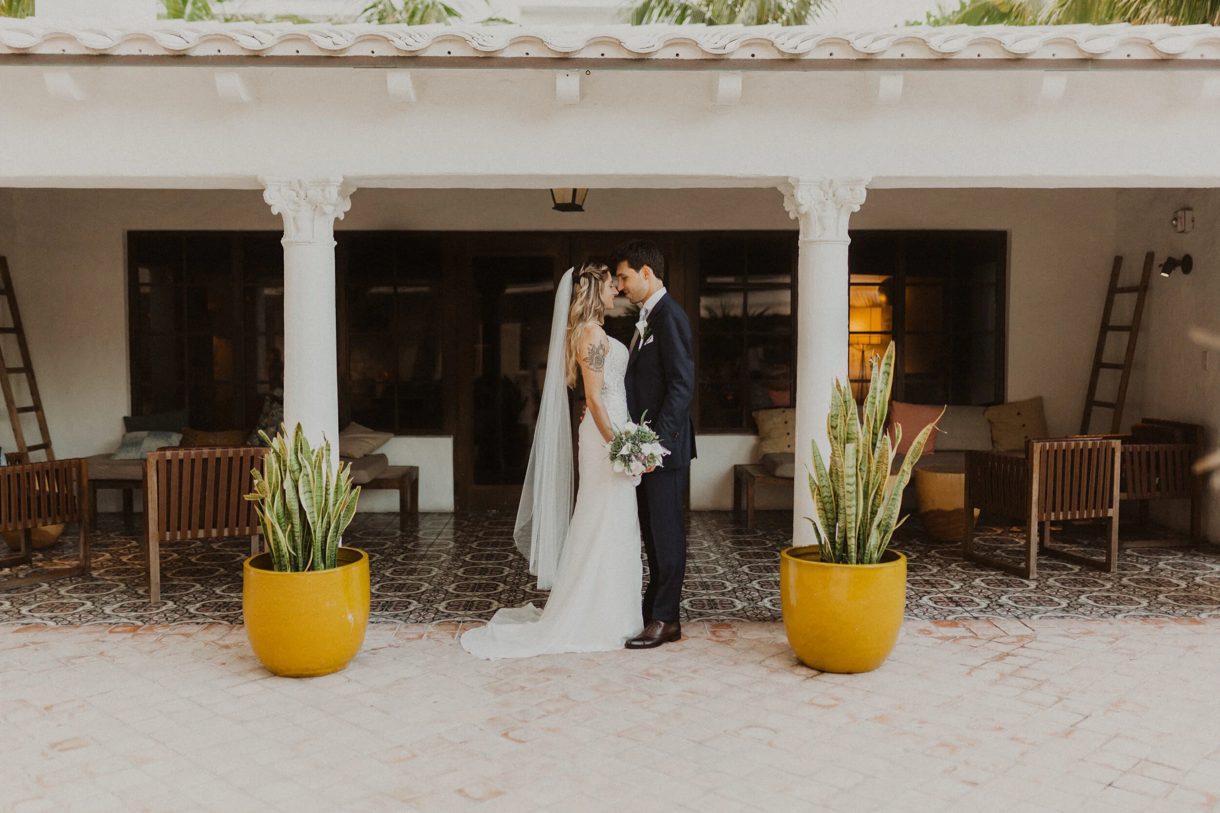Bride and groom standing together in an architectural courtyard framed by columns and potted plants, captured by a wedding photographer in Portland Oregon.