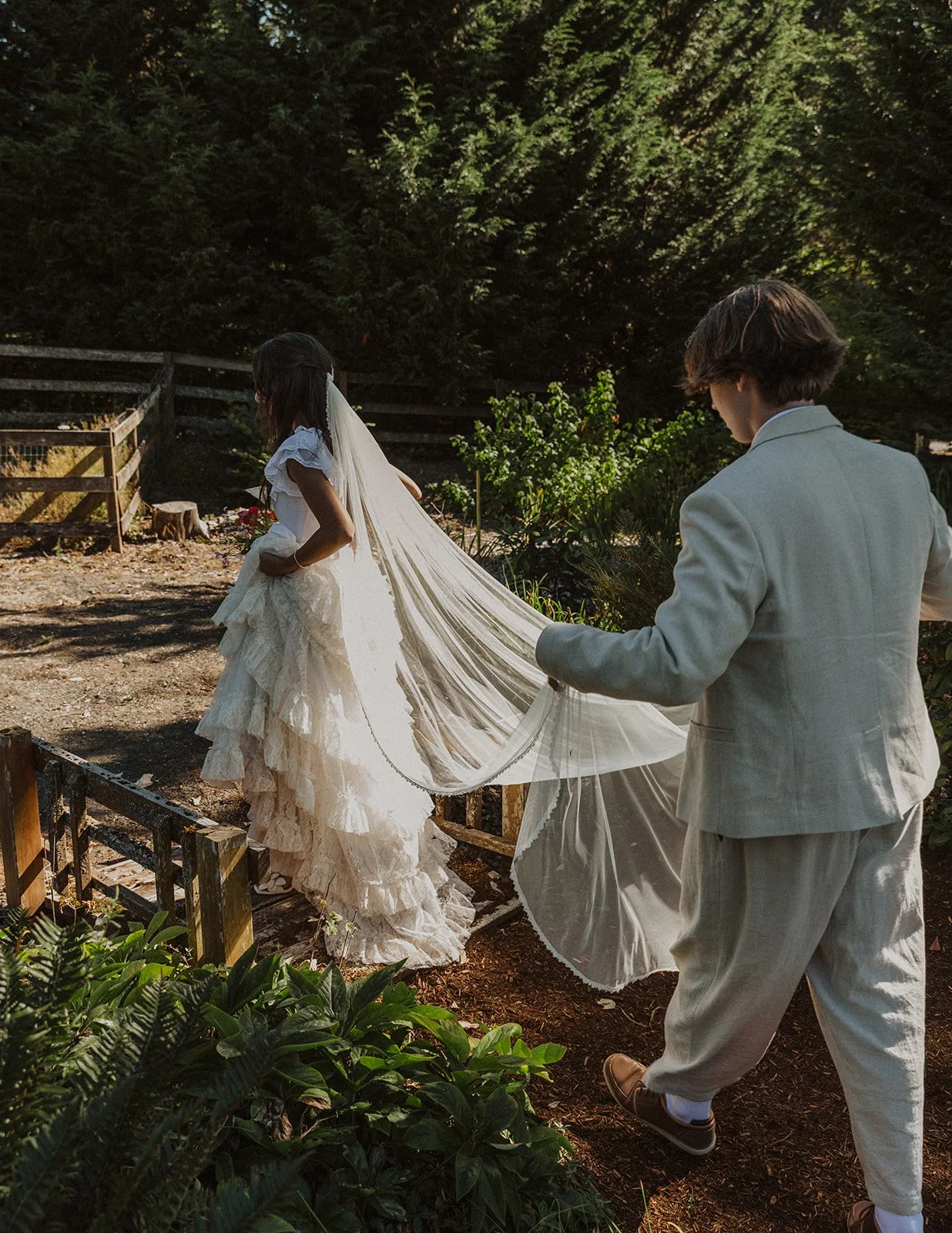 Groom lifting bride during a joyful first dance under glowing string lights and paper lanterns at an outdoor evening wedding