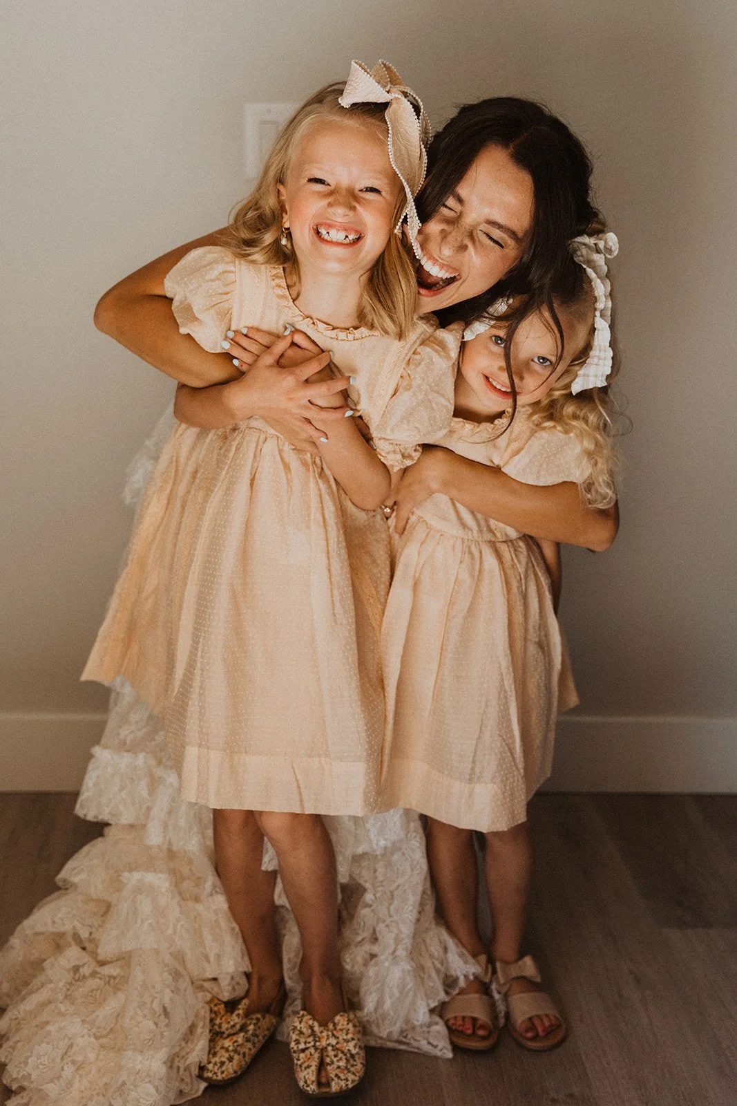 Bride hugging two children during joyful wedding morning moment indoors