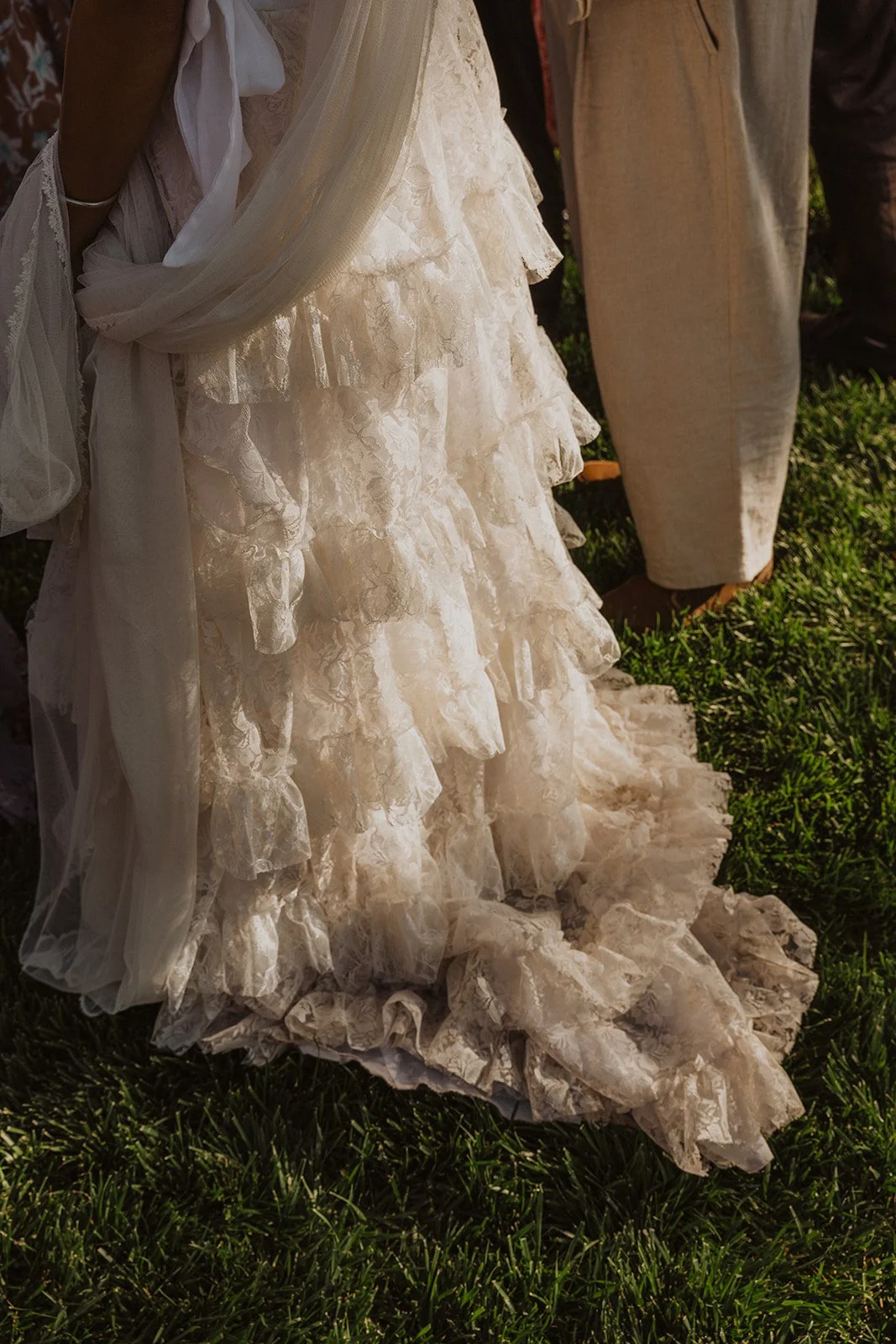 Bride holding a cascading bouquet stepping carefully across stones while the groom assists her during an outdoor garden wedding