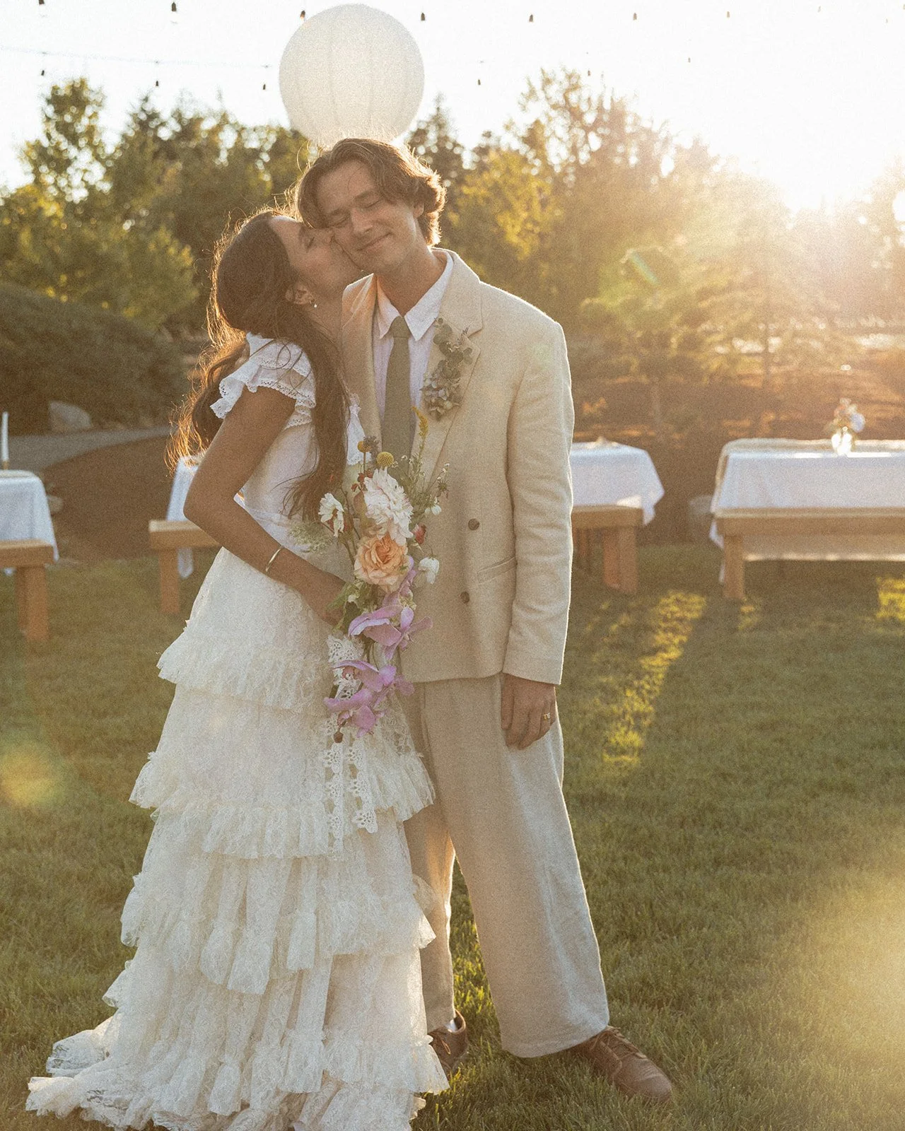 Bride kissing groom’s cheek during golden hour reception