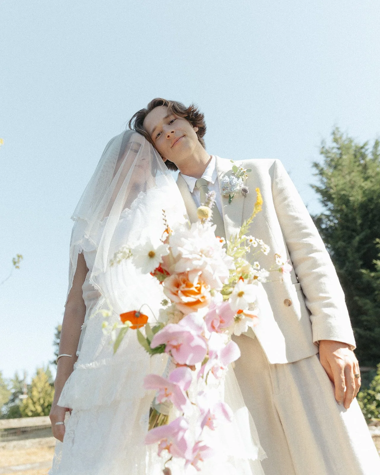 Close-up of couple with vibrant wedding bouquet in natural outdoor setting