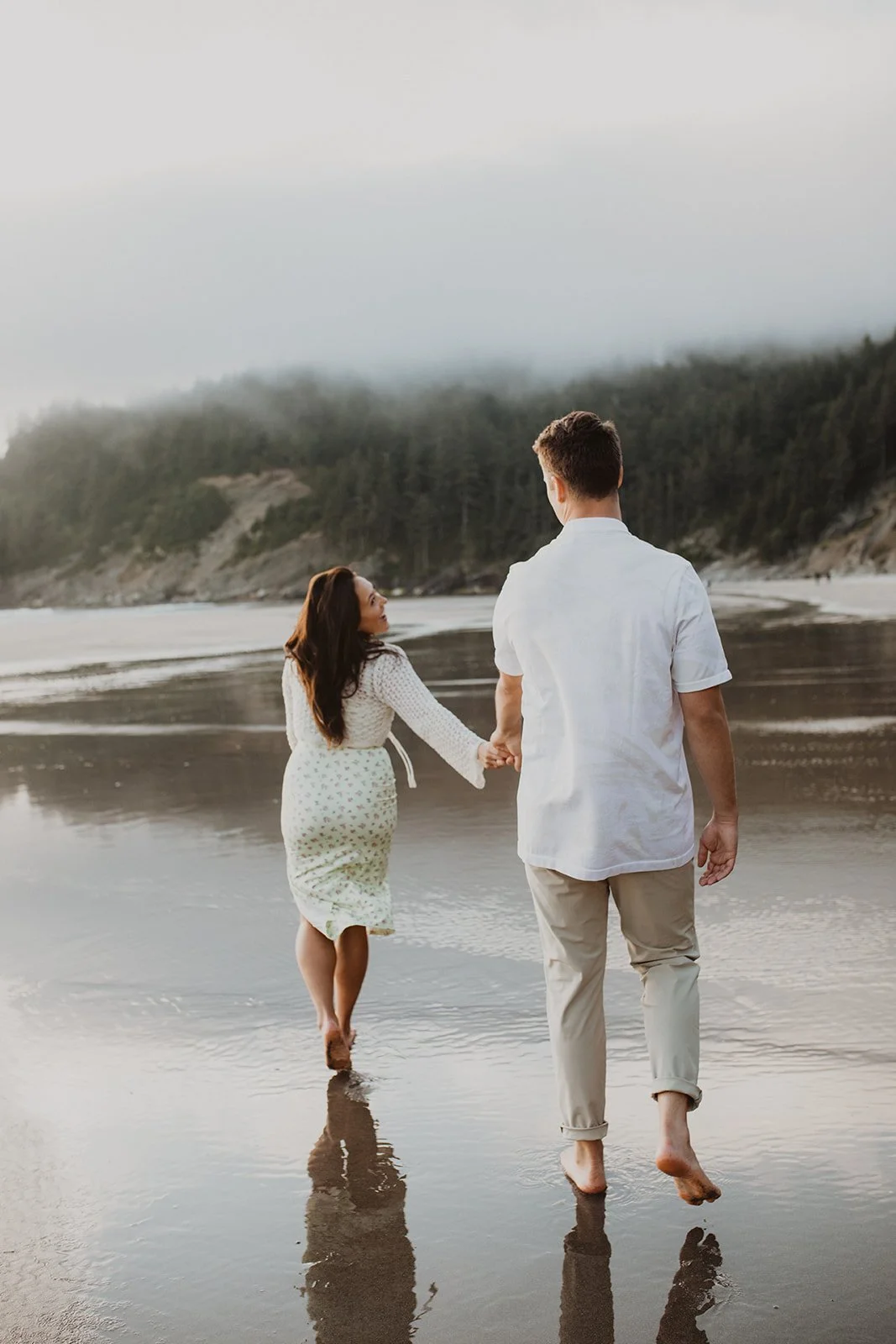 Couple walking barefoot along the Oregon coast during an intimate engagement session at sunset