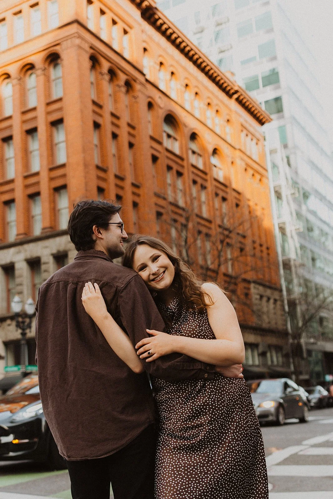 Couple hugging on a downtown Portland street with historic architecture during an urban engagement session