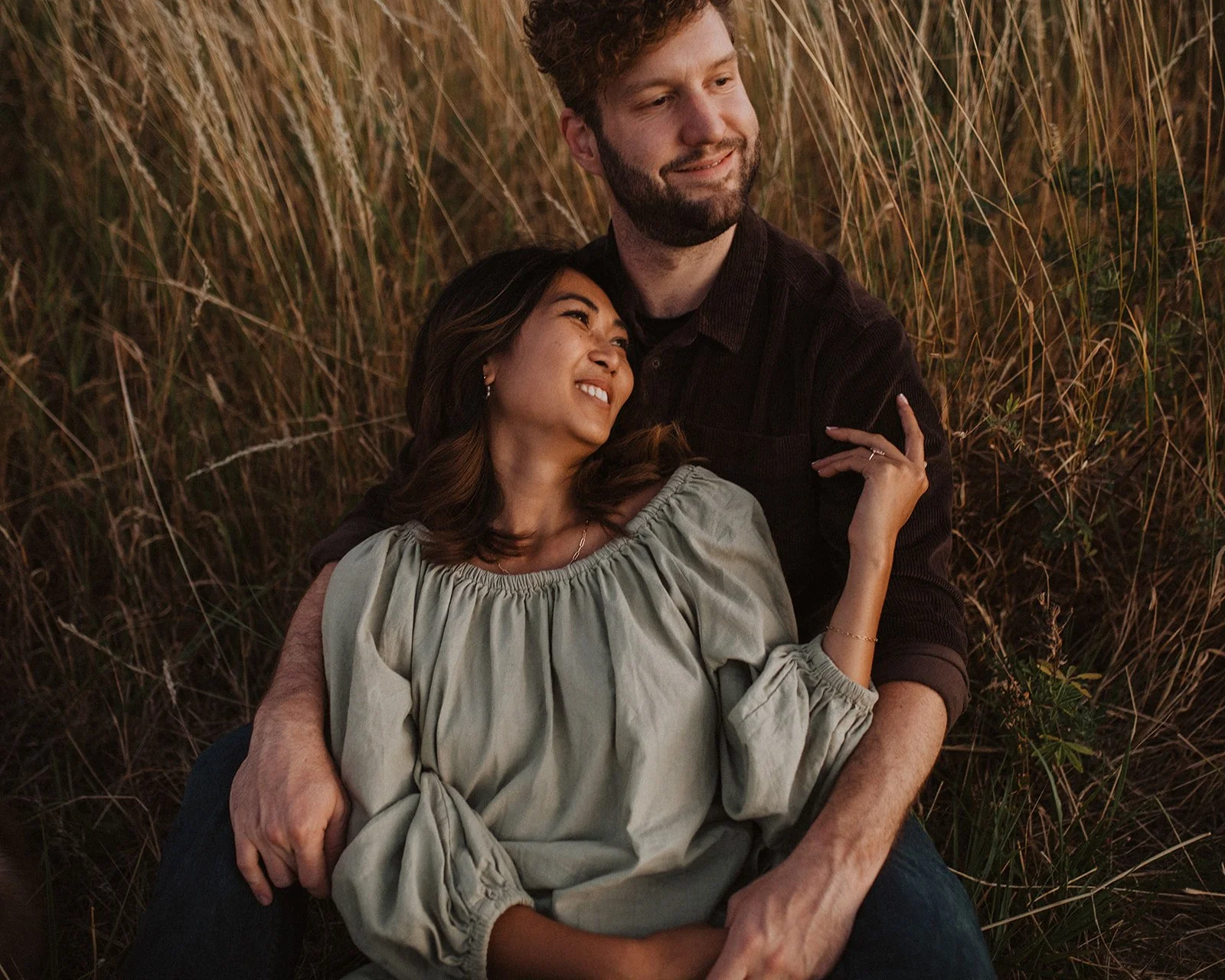 Couple embracing in tall grass during an Oregon engagement photo session at golden hour