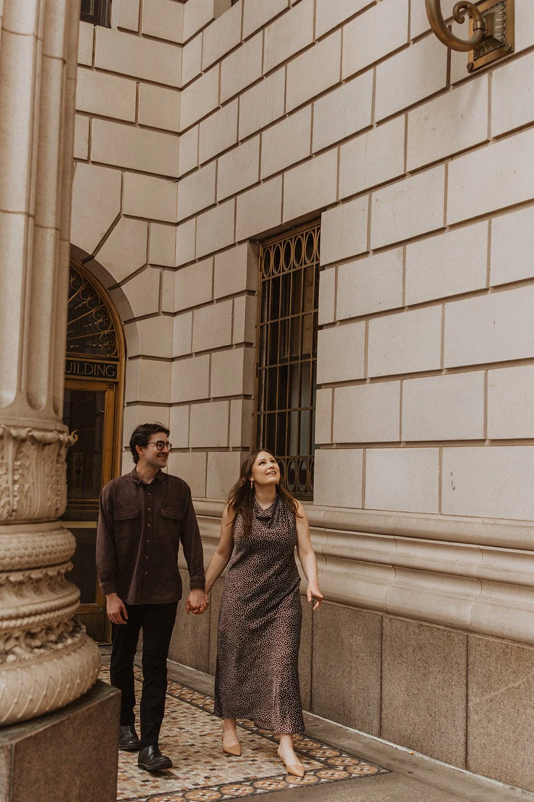 Couple holding hands and walking through downtown Portland with classic architecture