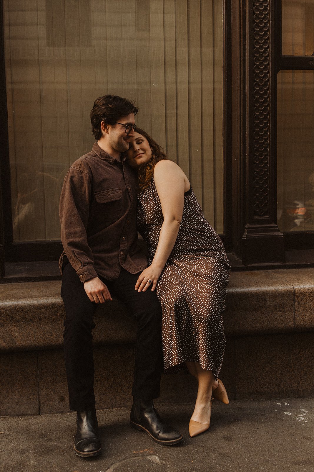Couple sitting together outside a historic building during a romantic city engagement session