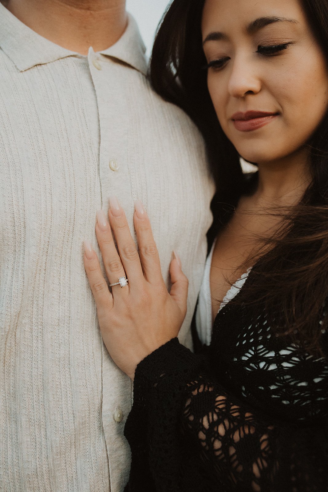 Close-up of engagement ring on woman’s hand resting on partner’s chest during a romantic engagement session