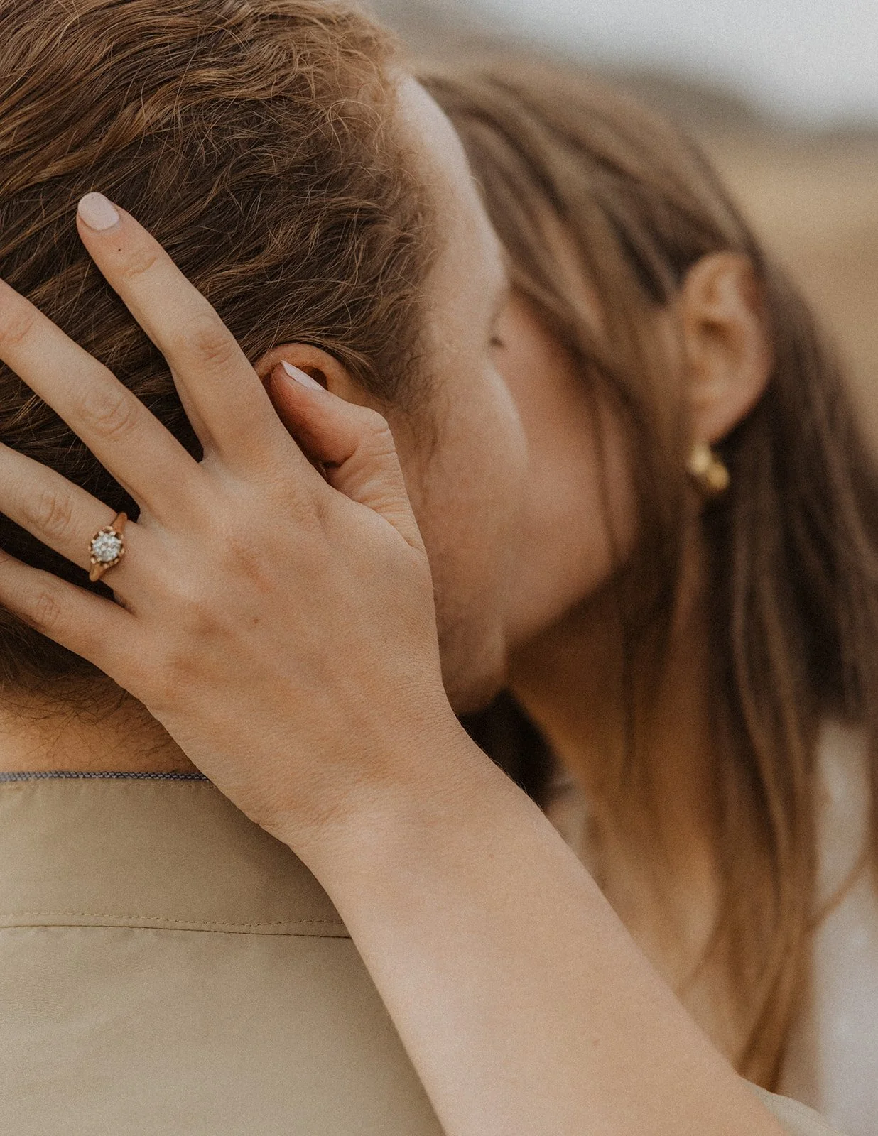 Close-up of engagement ring on woman’s hand resting on partner’s shoulder during intimate Oregon coast engagement moment
