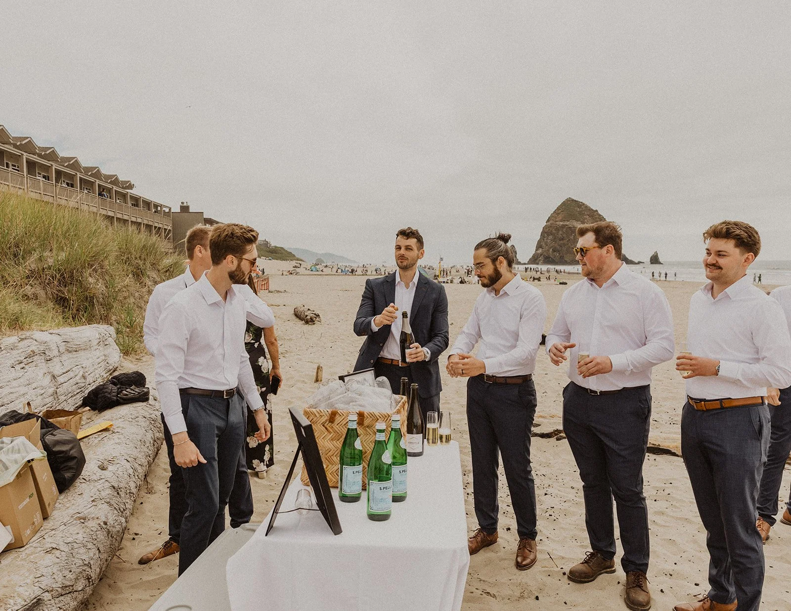 Groomsmen gathered on Cannon Beach before the ceremony with Haystack Rock in the background during an intimate Oregon coast wedding