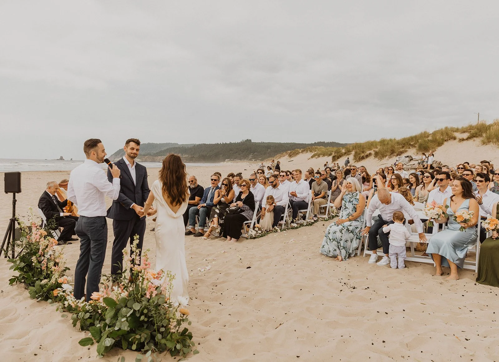 Couple exchanging vows during an intimate Cannon Beach Oregon wedding ceremony with guests gathered on the beach