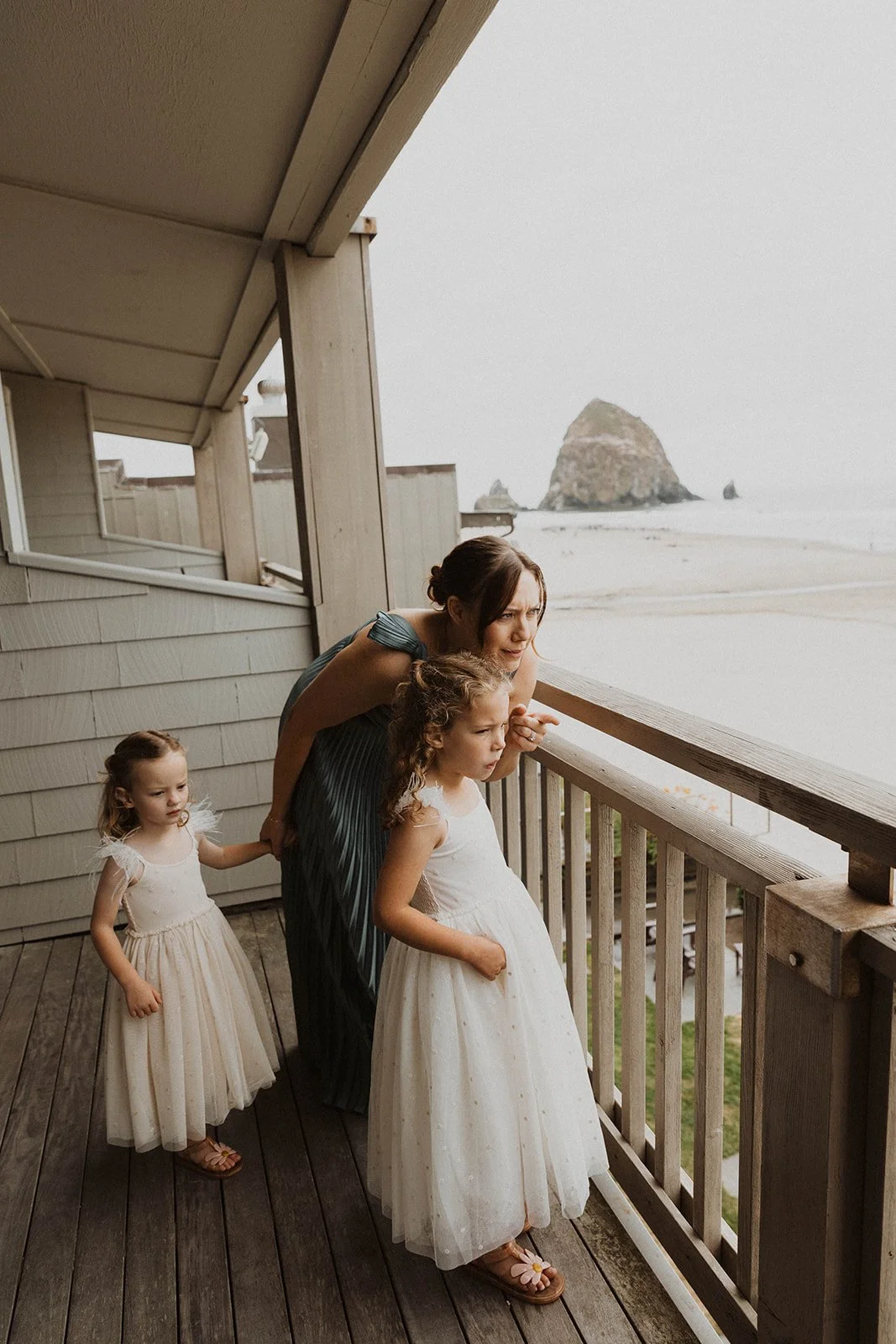 Bridesmaid and flower girls looking out toward Haystack Rock from a balcony before a Cannon Beach wedding ceremony