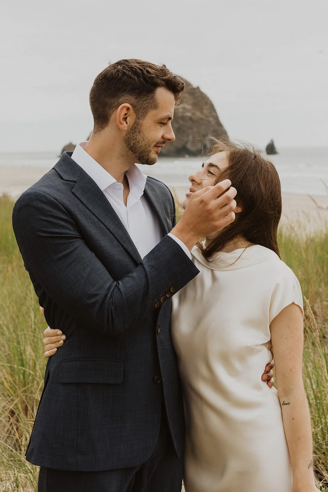 Close-up portrait of a newlywed couple embracing in the grassy dunes along the Oregon coast