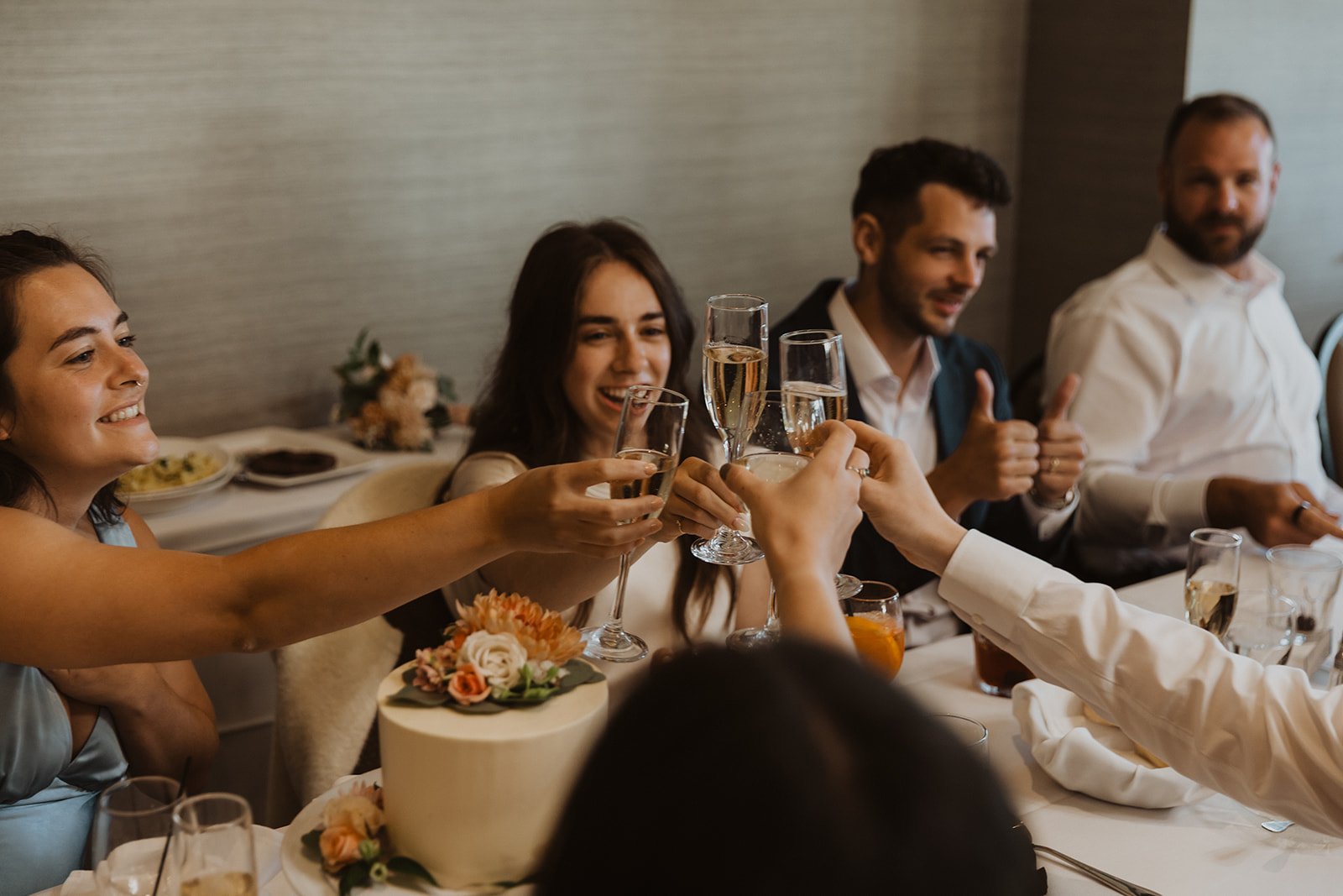Bride and guests raising champagne glasses during a joyful intimate wedding reception toast
