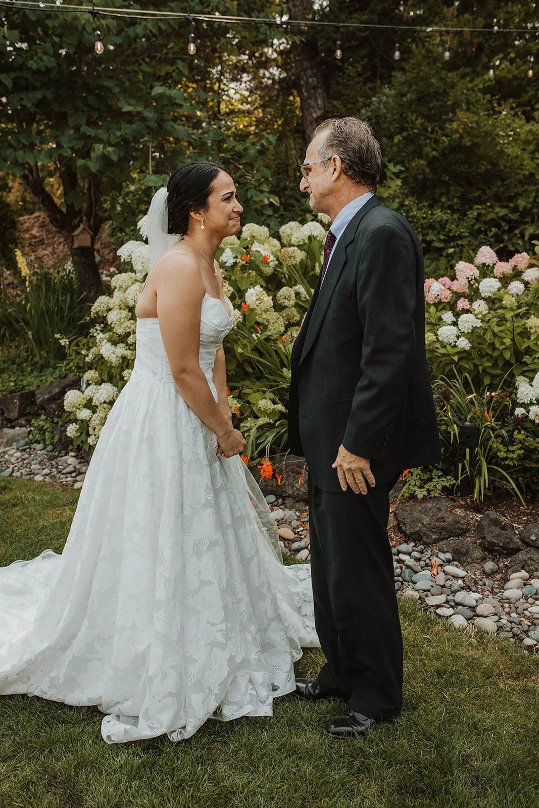 Bride kisses her father on the cheek while holding a colorful summer bouquet with mountains in the background at Cape Horn Estate wedding venue.