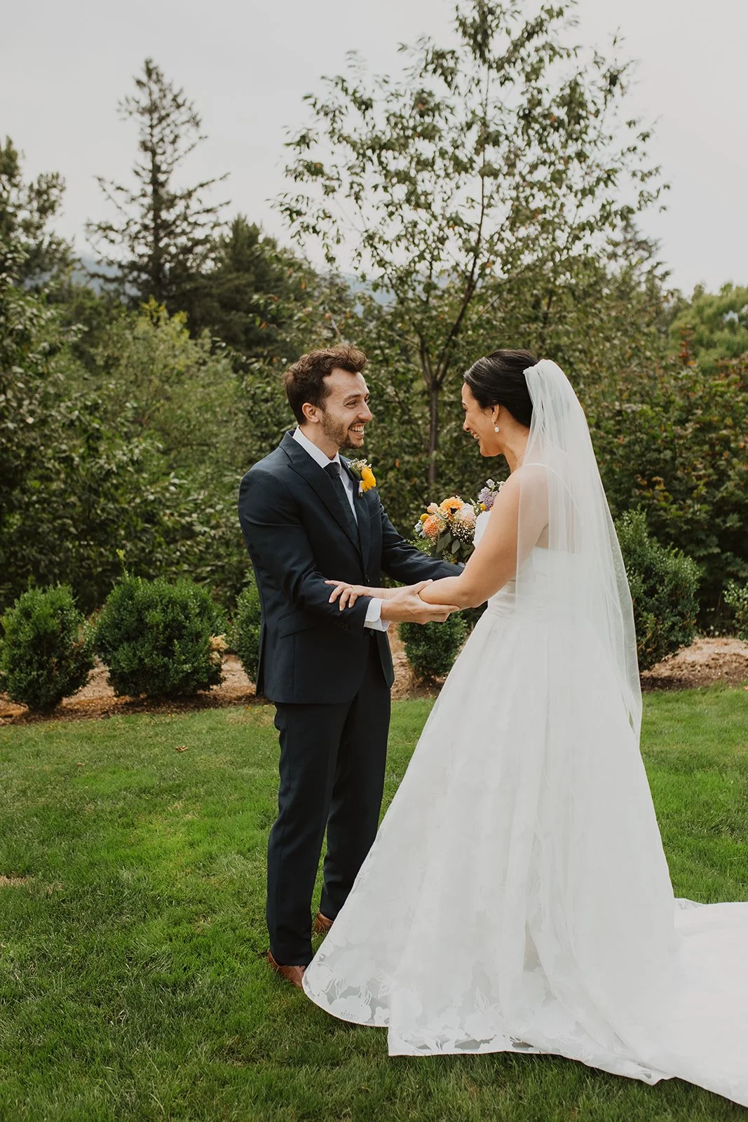 Bride taps the groom on the shoulder before their first look in a romantic outdoor wedding garden with blooming hydrangeas.