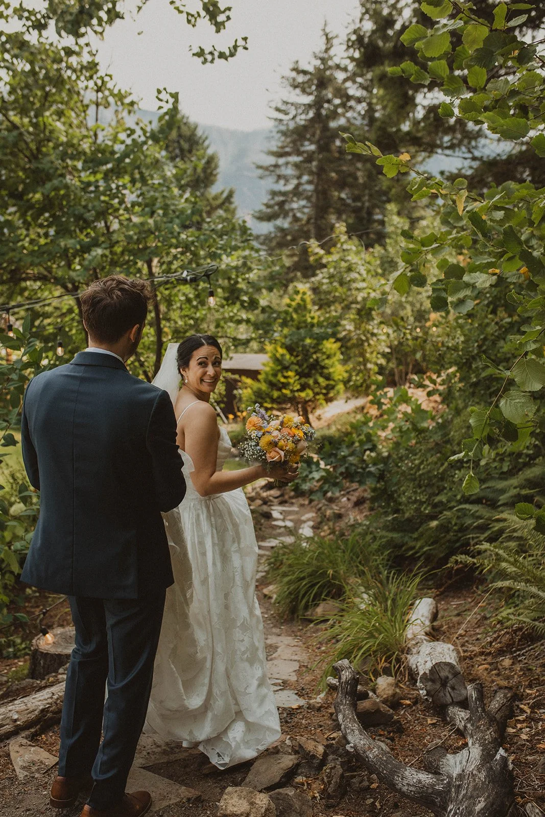 Bride and groom kissing in front of mountain views and hydrangea bushes during golden hour at an outdoor garden wedding venue.
