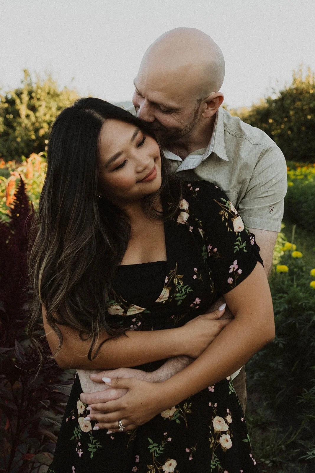 Engaged couple embracing among colorful flowers during a romantic flower farm engagement session at sunset