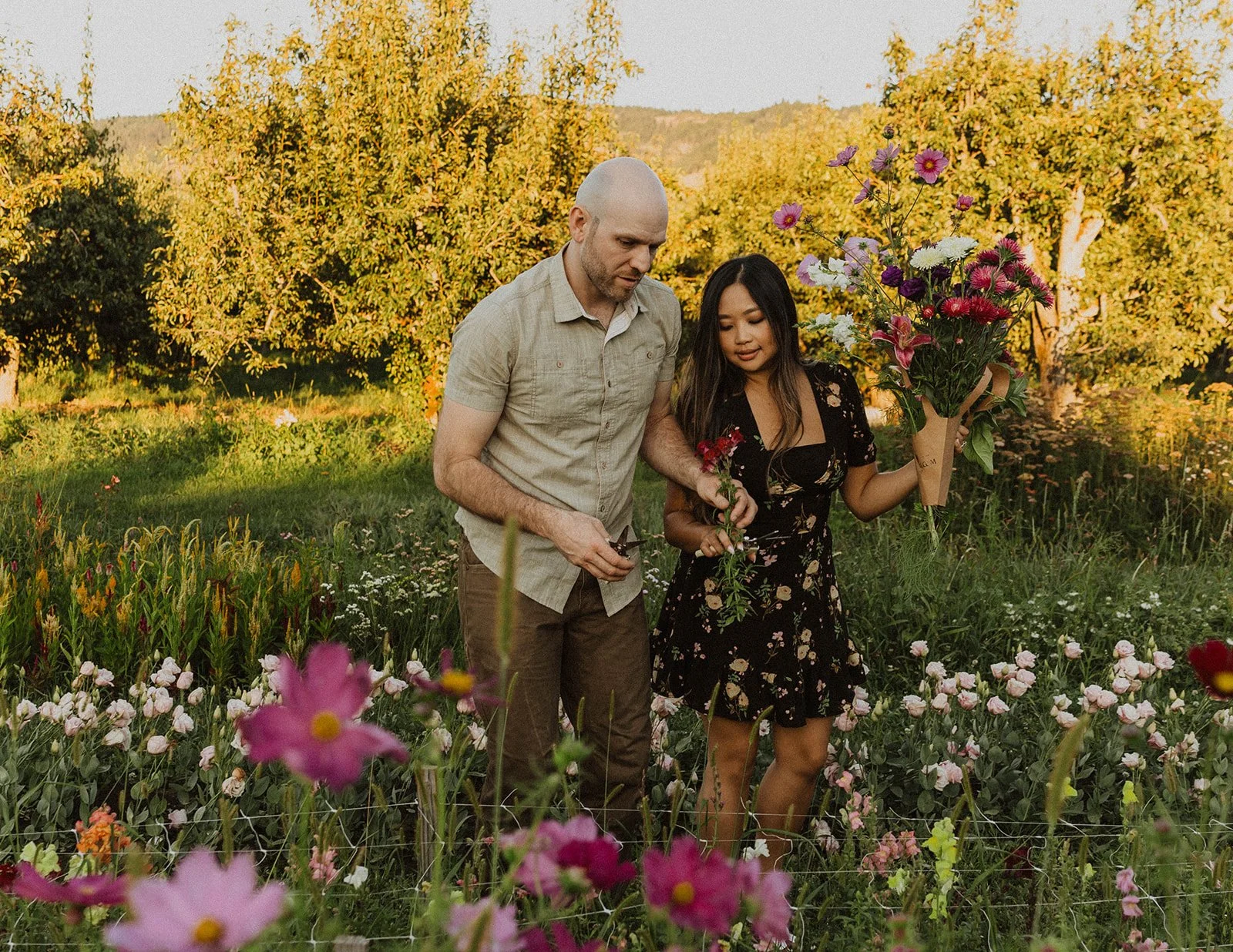 Engaged couple gathering fresh flowers and creating a bouquet during a flower farm engagement session.