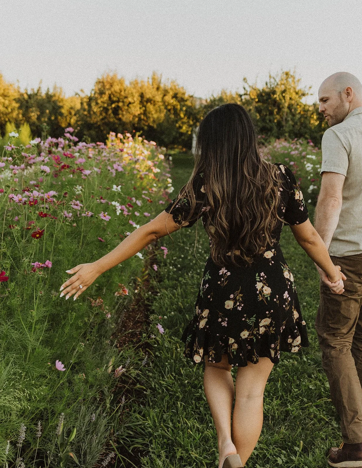 Couple holding hands and walking through blooming flower fields during a romantic Oregon engagement session.