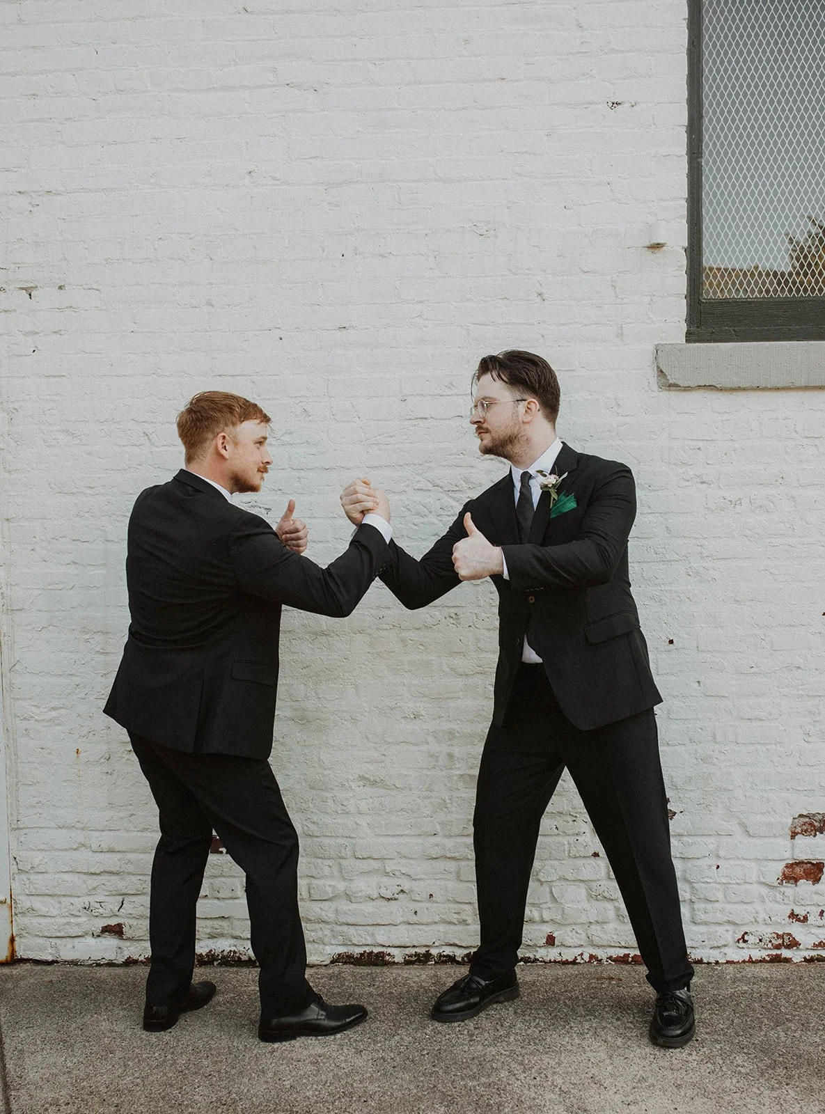 Groom and groomsman laughing together during wedding portraits outside The Castaway in Portland.
