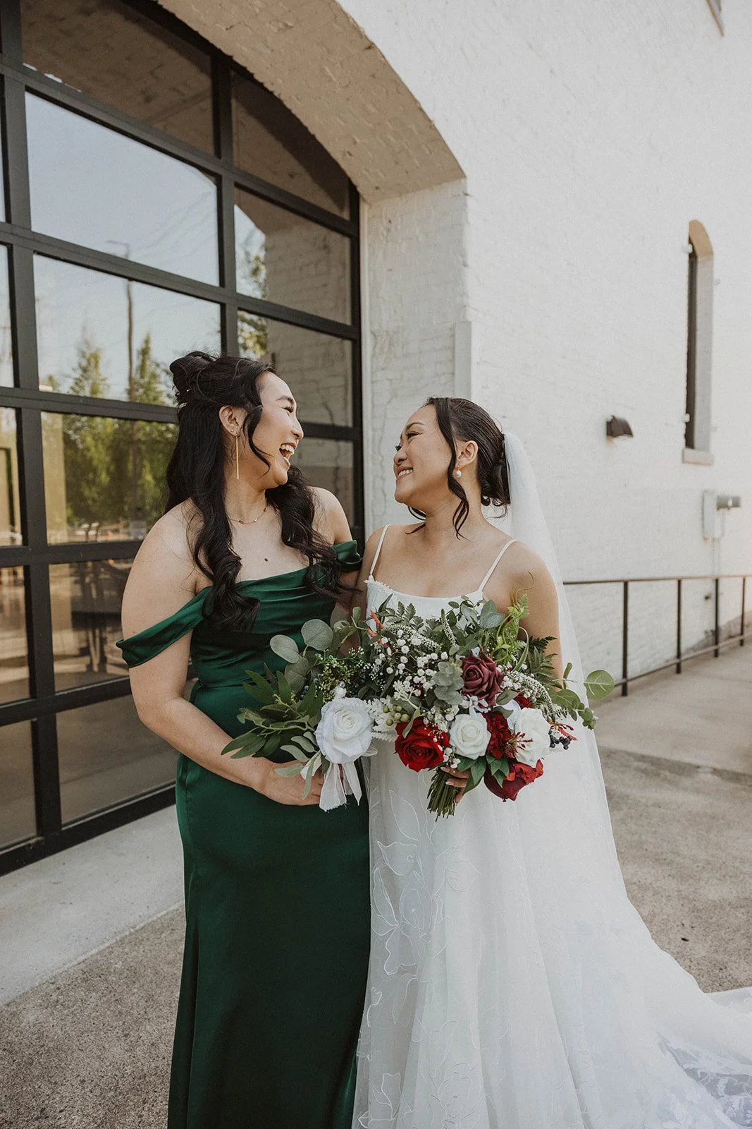 Bride and bridesmaid smiling together during wedding portraits at The Castaway in Northwest Portland.