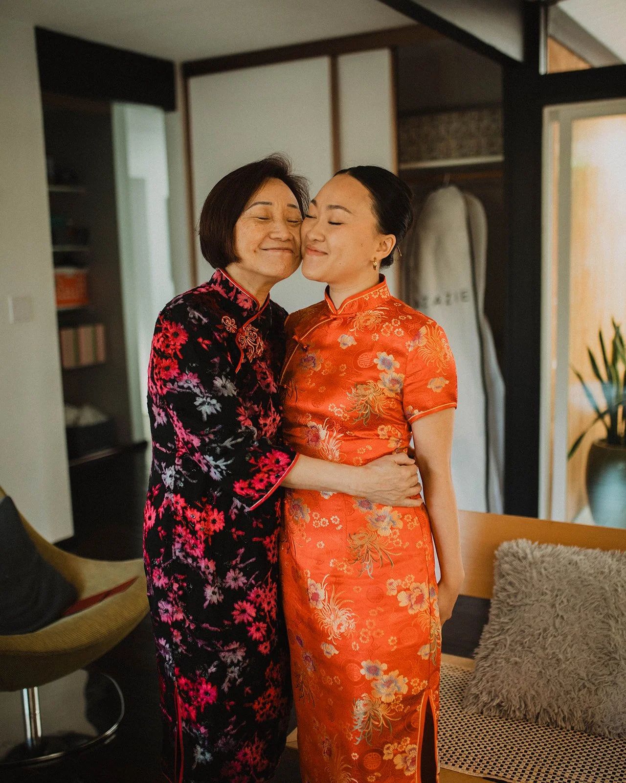 Bride in a red embroidered cheongsam shares a heartfelt embrace with her mother during wedding preparations before the ceremony.