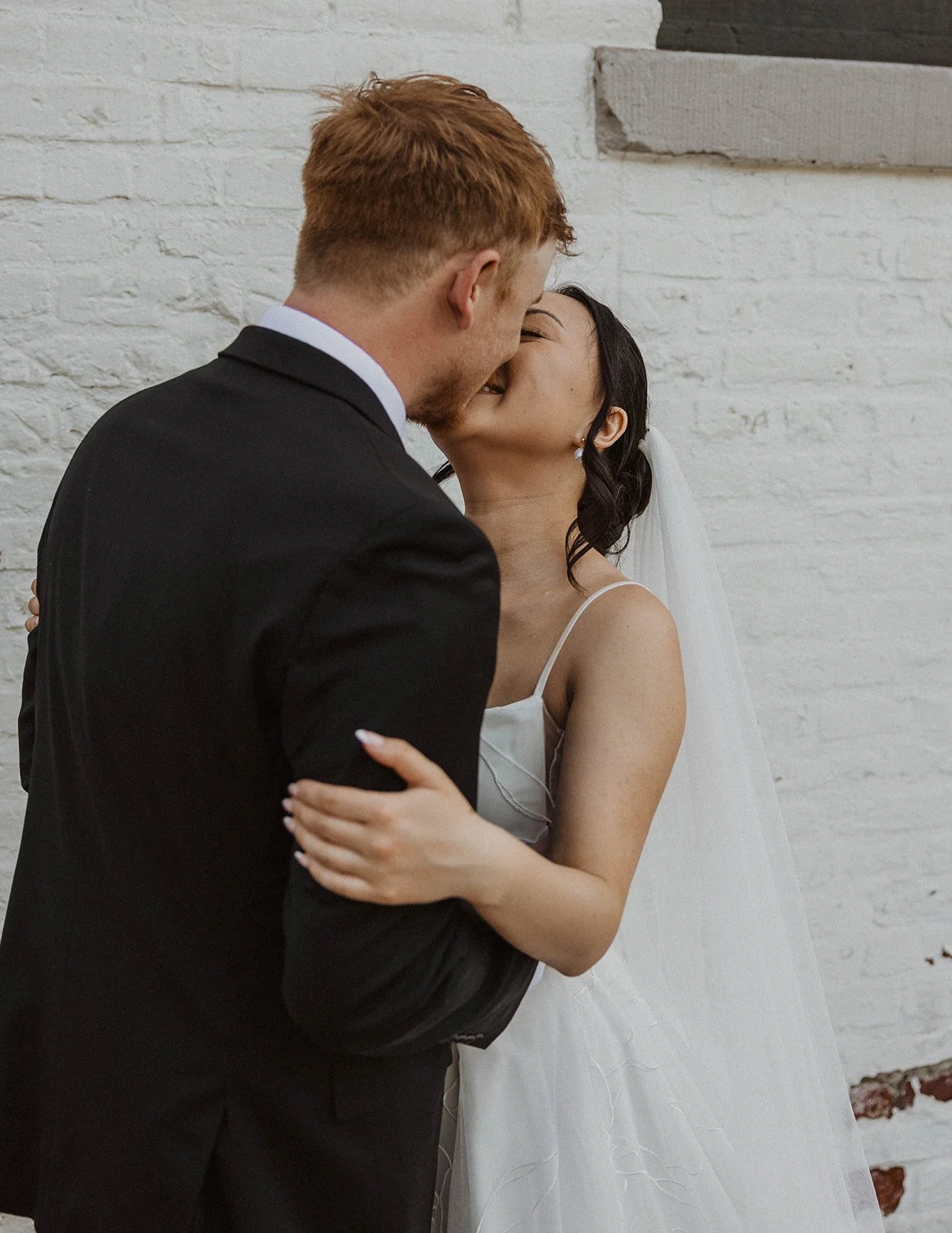 Bride and groom share a kiss during romantic wedding portraits outside their Portland wedding venue.