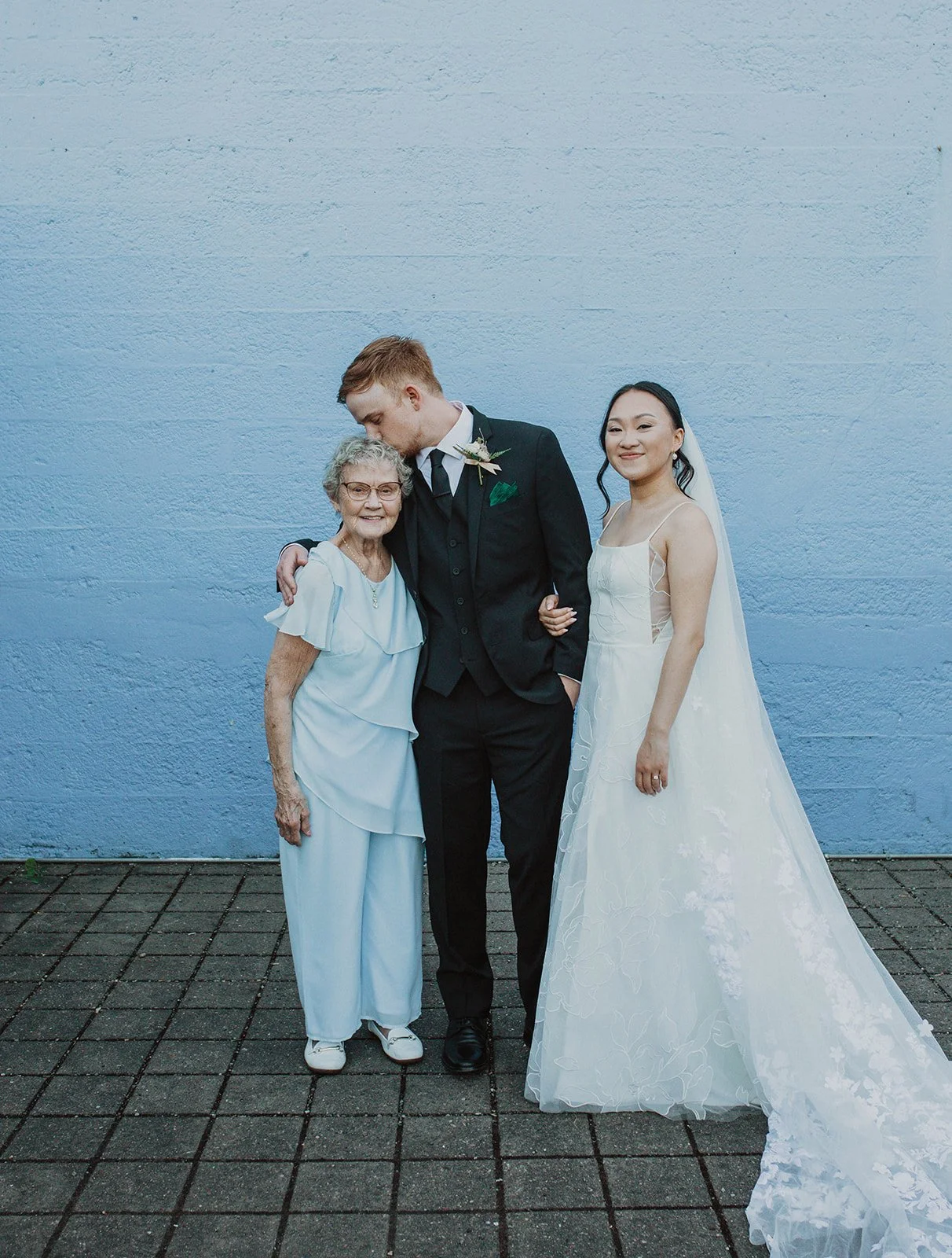 Bride and groom pose with the groom's grandmother during family portraits following their Oregon wedding ceremony.