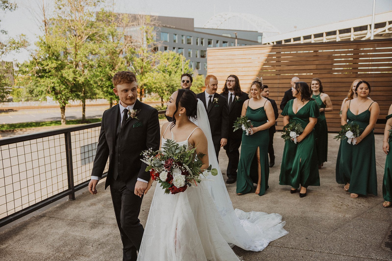 Bride and groom walk with their wedding party during portraits outside The Castaway in Northwest Portland.