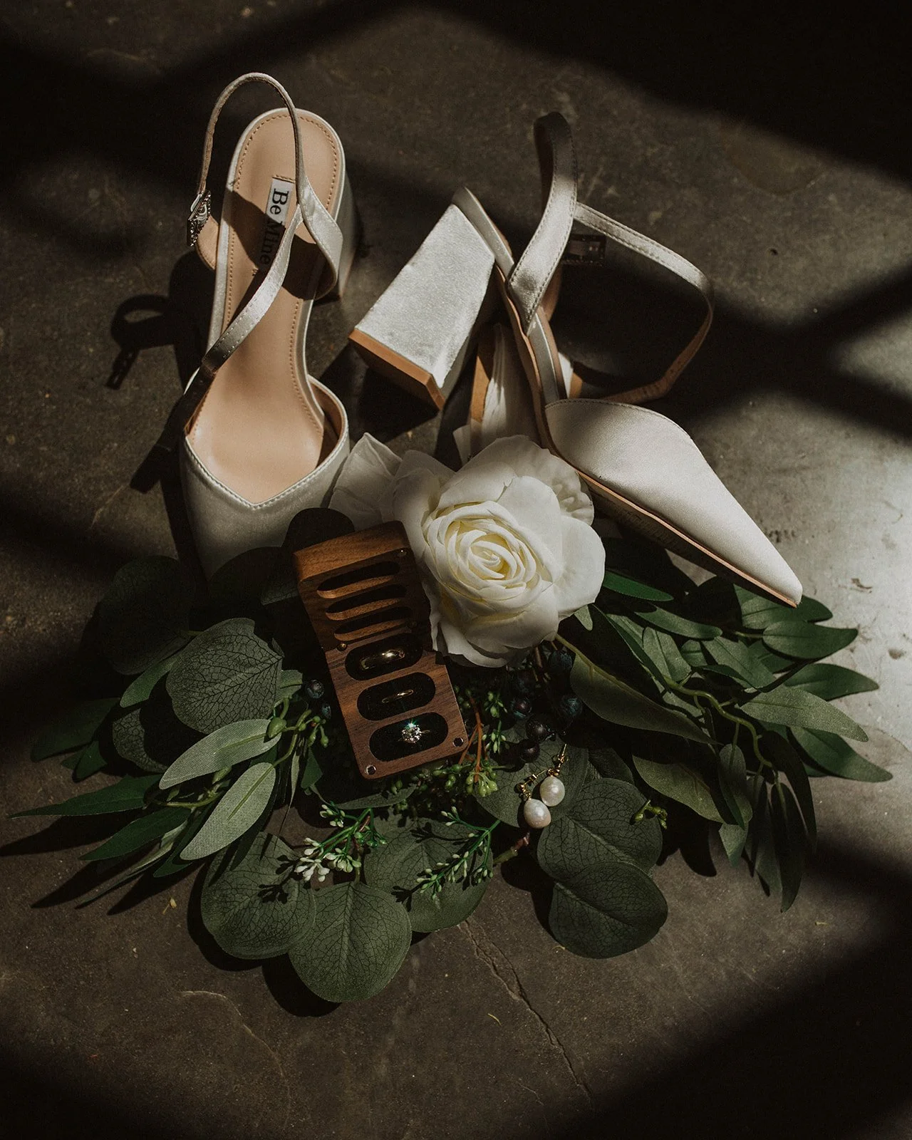 Wedding rings, bridal shoes, pearl earrings, and greenery arranged for detail photographs before a Portland wedding.
