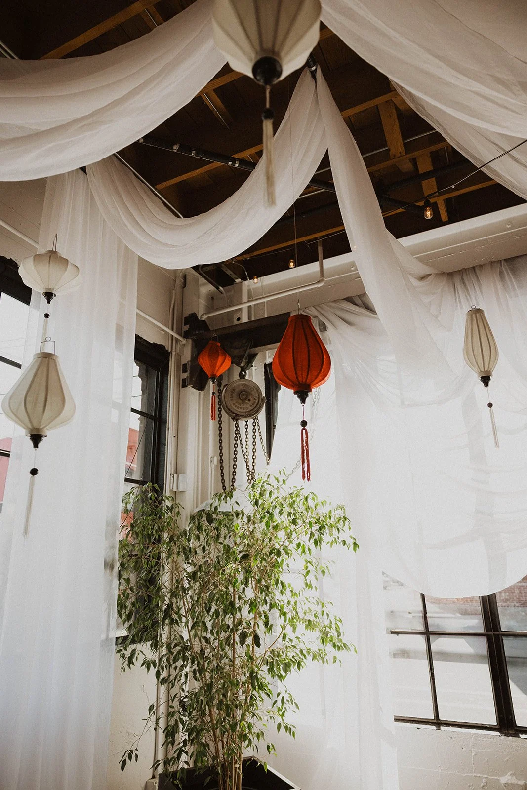 Traditional lanterns and flowing white drapery decorate The Castaway reception space for a Portland wedding celebration.