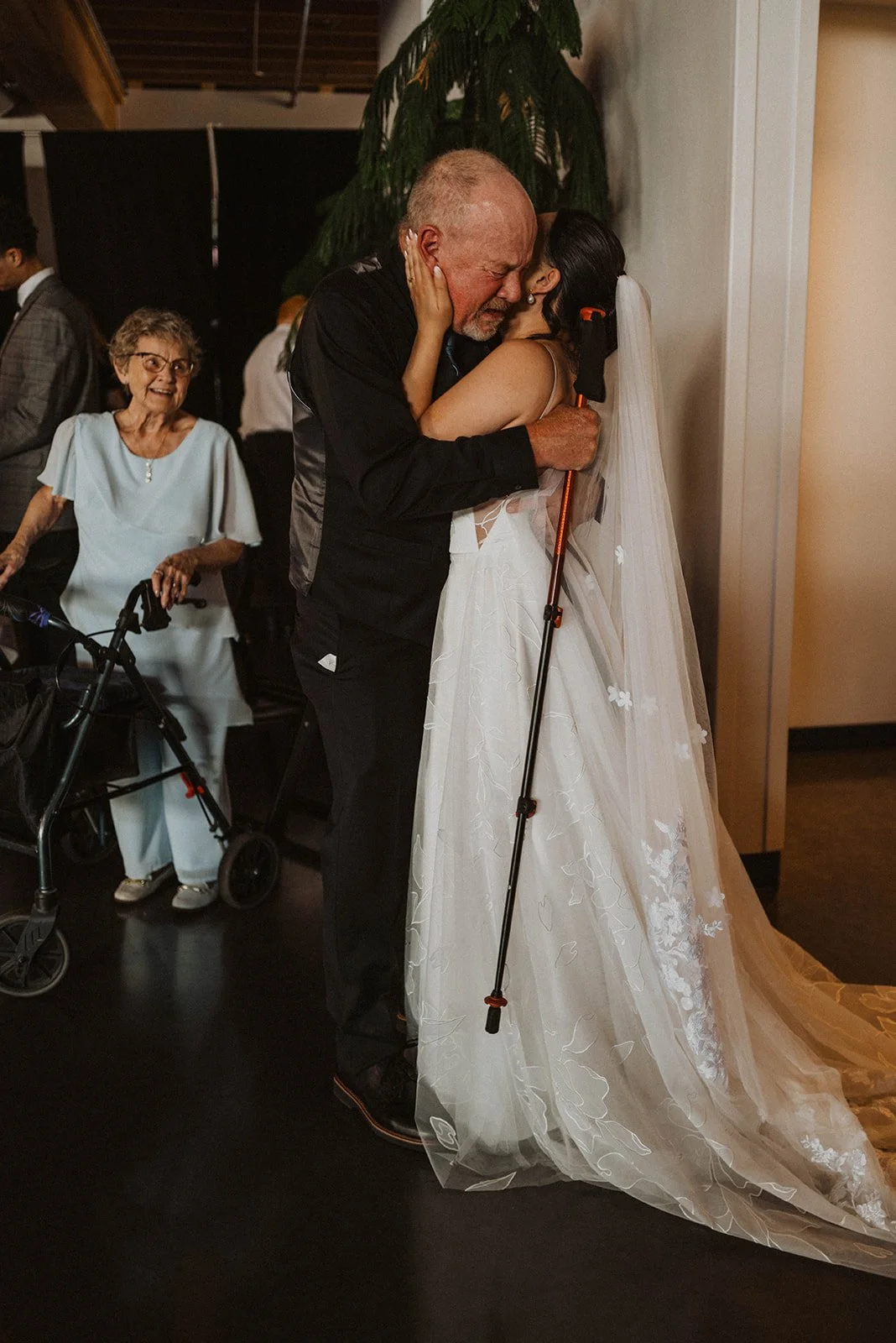 Bride shares an emotional hug with her grandfather during a wedding celebration in Oregon while family members look on nearby.