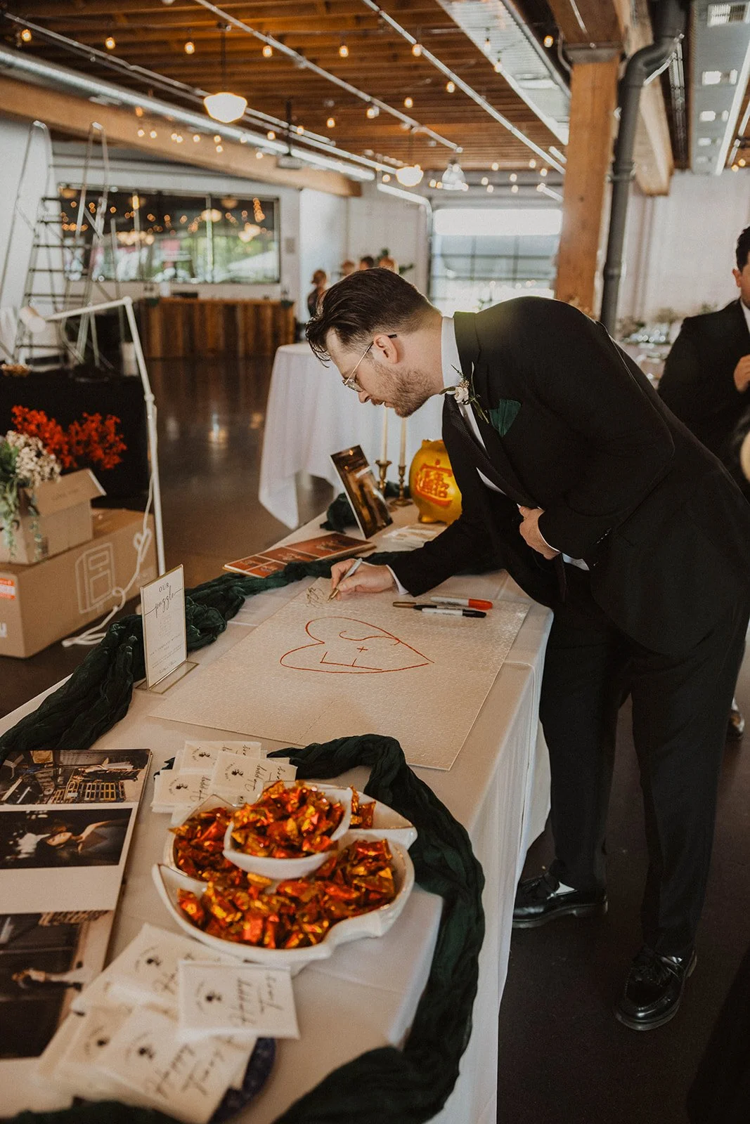 Wedding guest signs a custom guest book display during the reception at The Castaway wedding venue in Portland.
